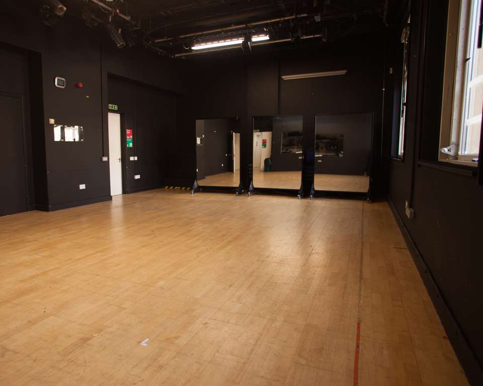 Versatile event space with polished wooden floor, ideal for workshops and gatherings.