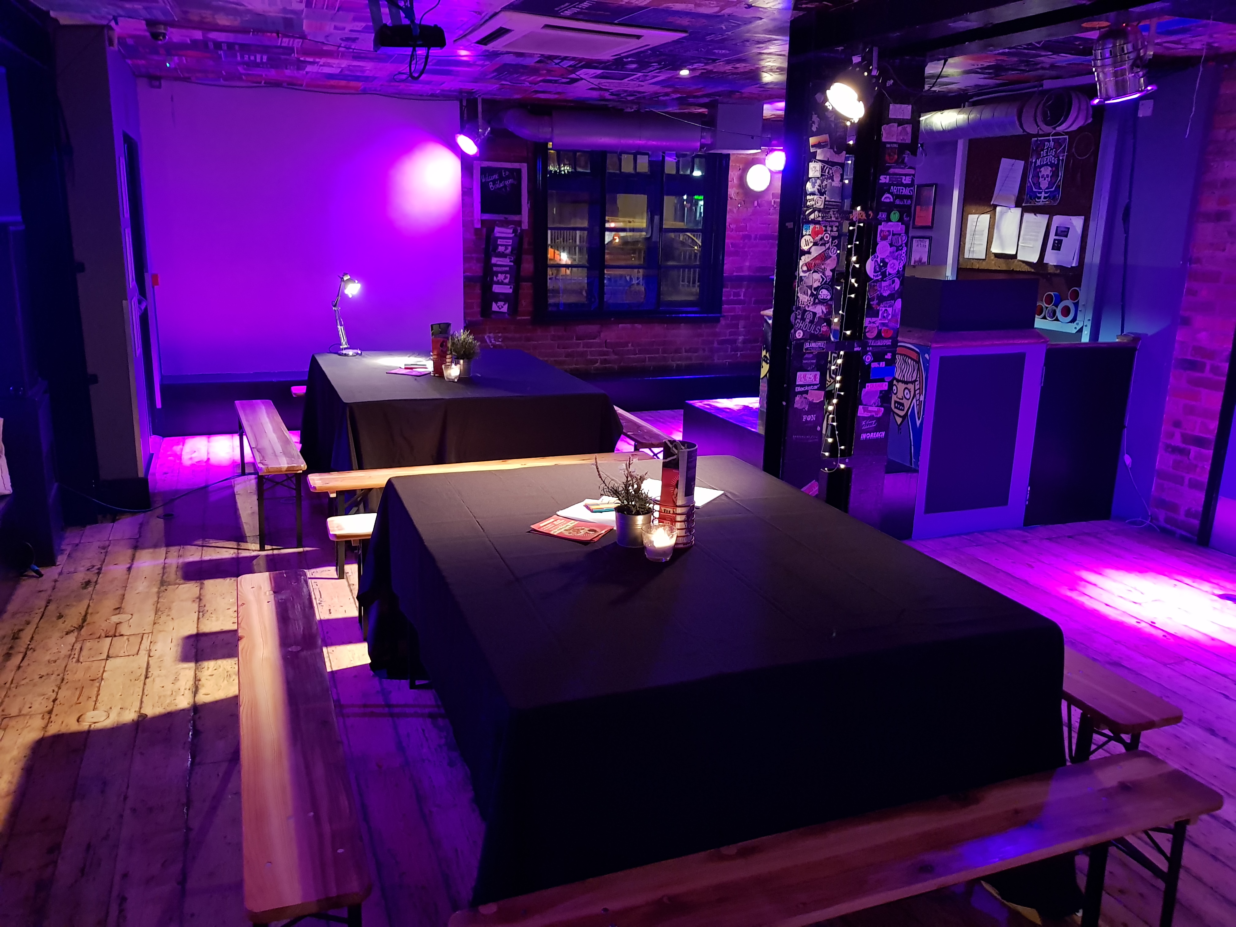 Main Room at The Boileroom with black tables and purple lighting for events.
