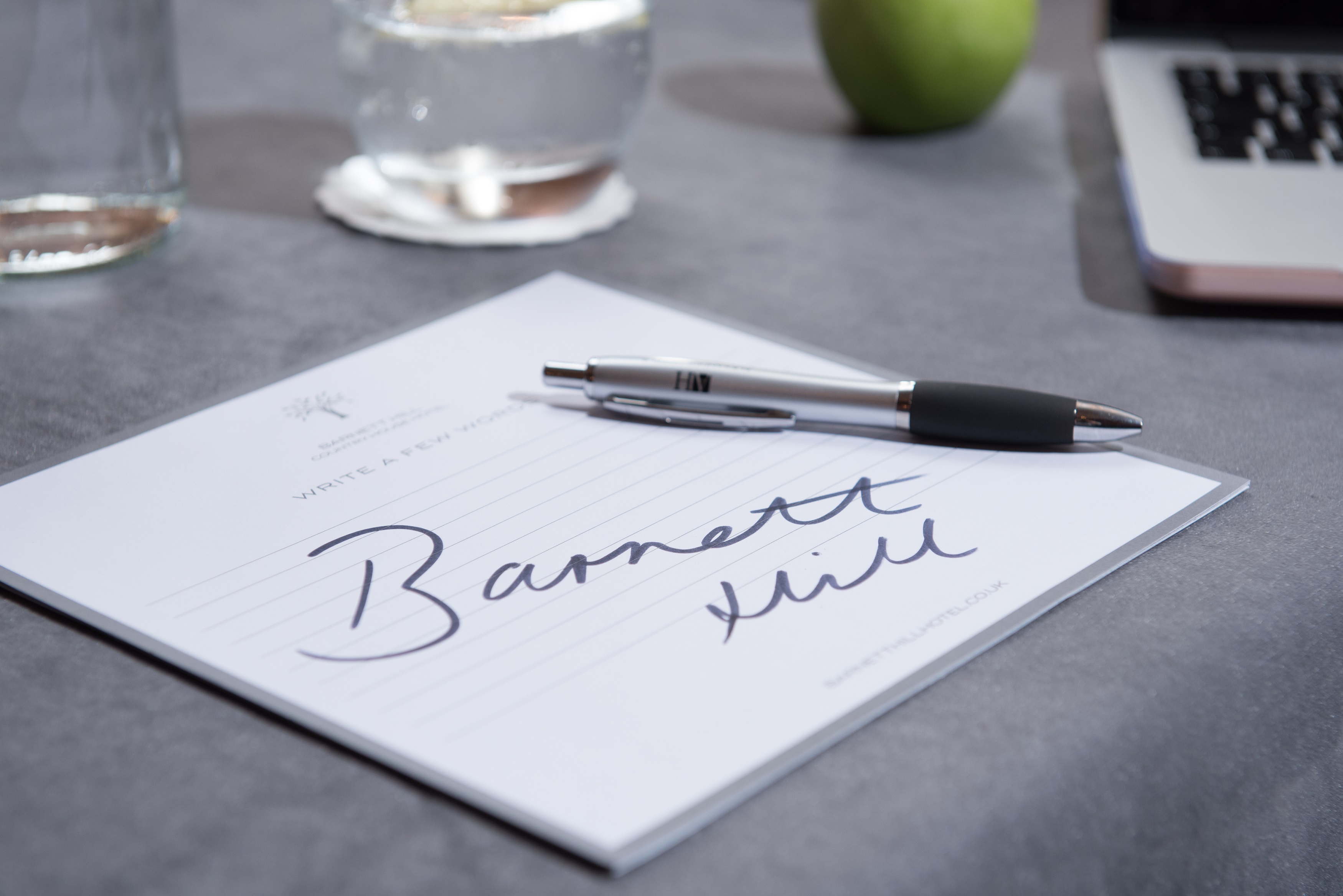 Meeting setup at Barnett Hill Hotel with personalized notepad, water, and apple.