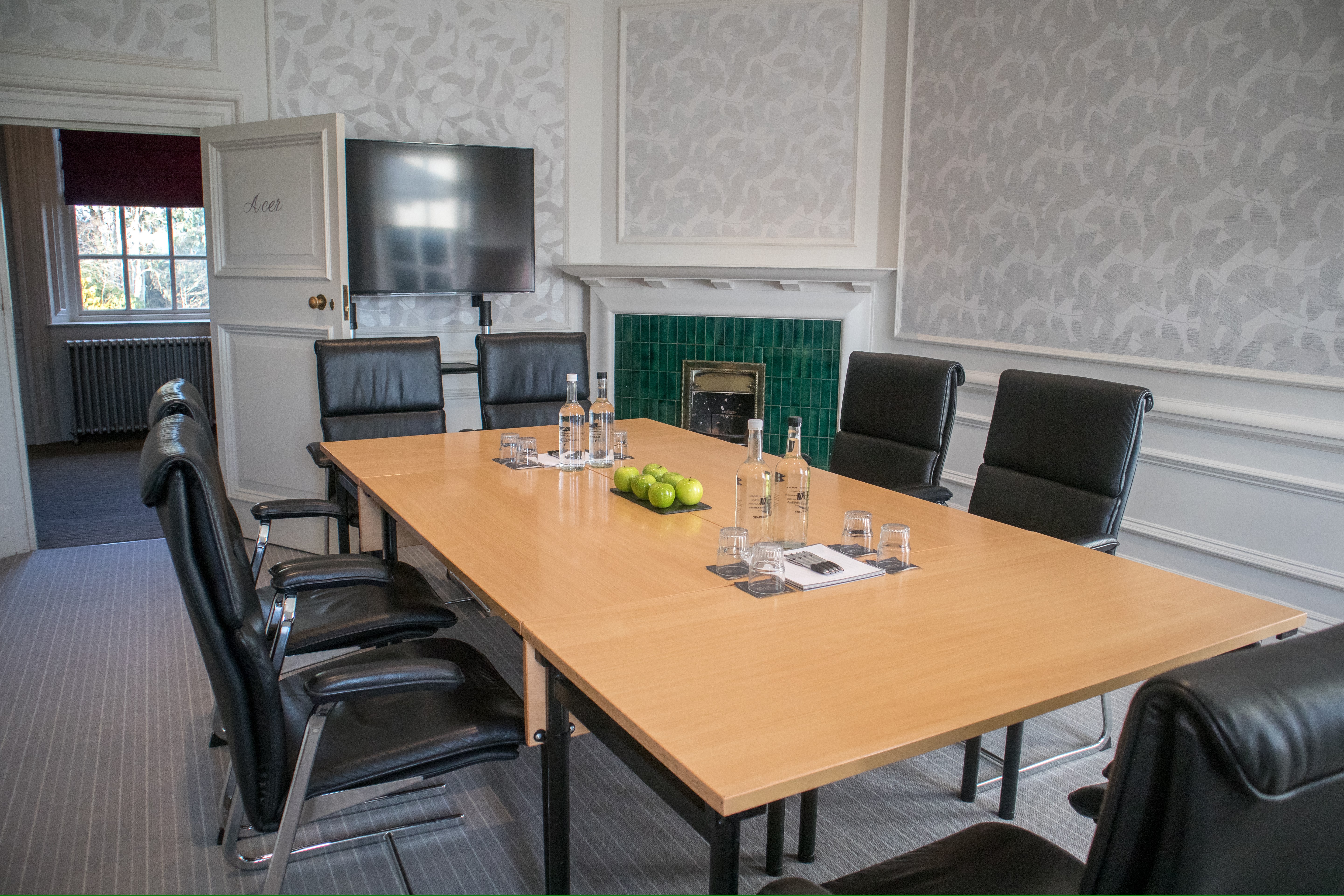 Modern meeting room at Barnett Hill Hotel with sleek table and wall-mounted screen.
