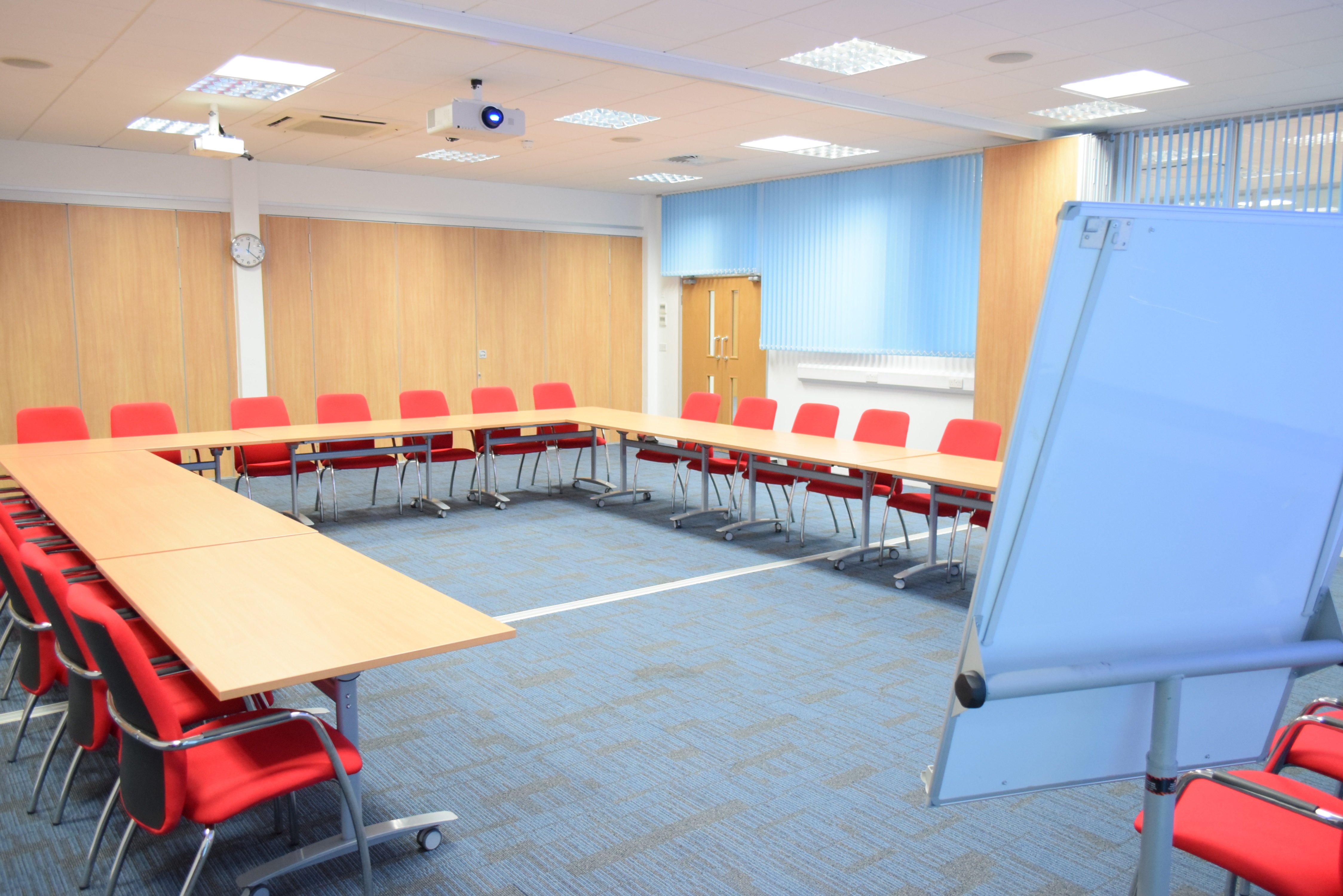 Conference room setup with U-shaped table, red chairs for collaborative workshops.