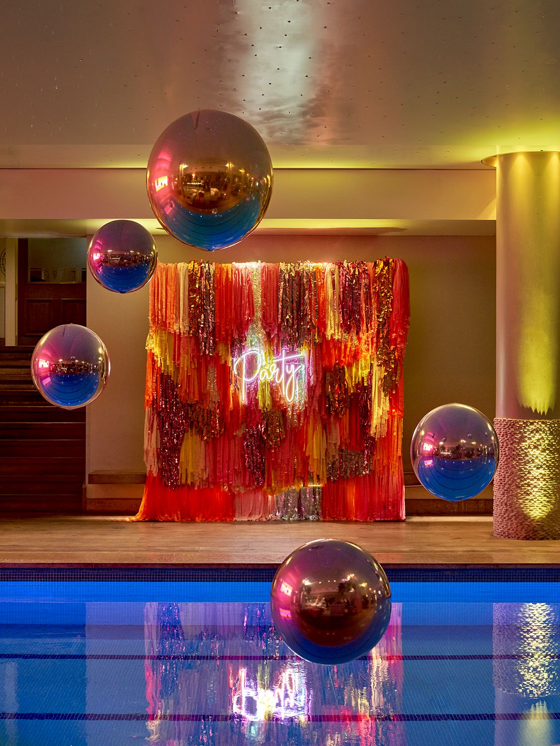 Vibrant Haymarket Hotel pool area with colorful fringe and neon "Party" sign for events.
