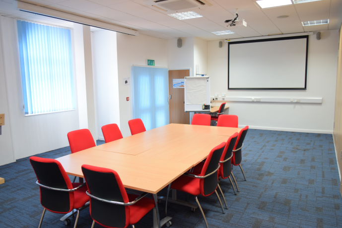 Spacious Meeting Room 1 at HAD with red chairs, ideal for workshops and presentations.