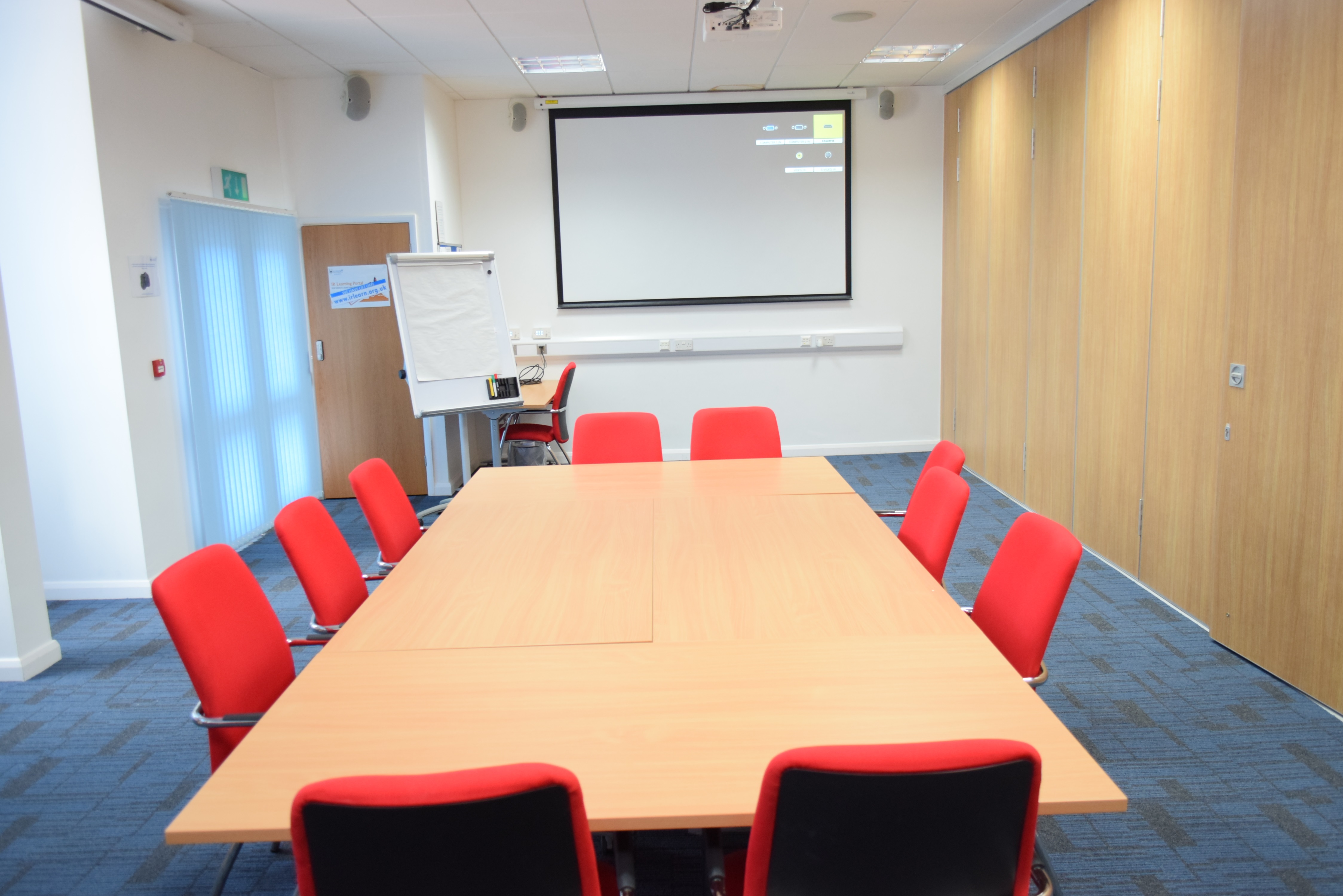 Meeting Room 1 at HAD with ergonomic red chairs for collaborative meetings and presentations.