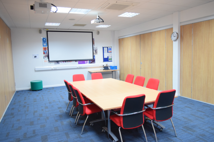 Meeting room 2 at HAD with a large wooden table and red chairs for collaborative events.