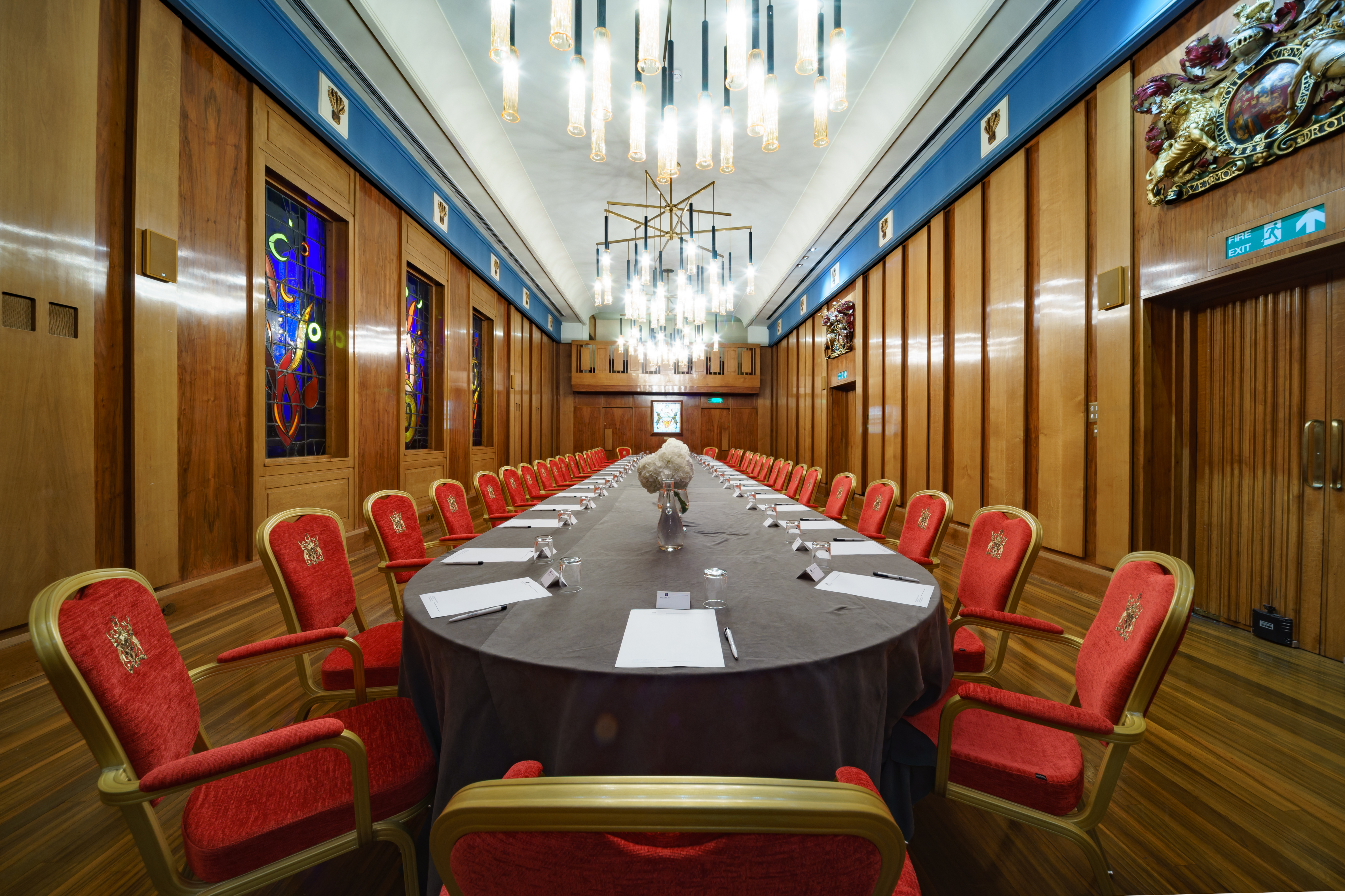 Elegant Livery Hall meeting room with long table and plush red chairs for corporate events.