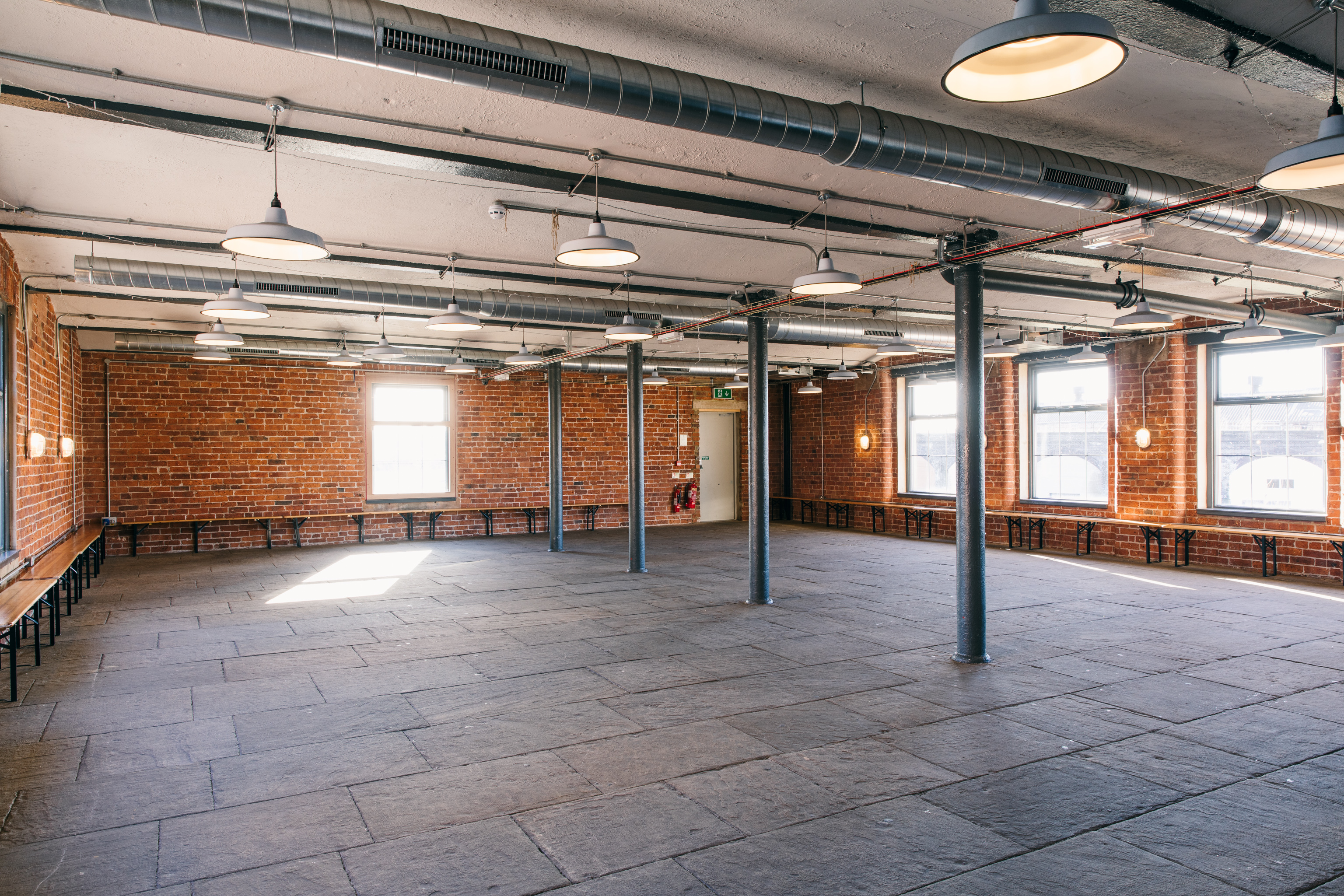 Spacious industrial event venue with exposed brick, ideal for creative workshops and meetings.