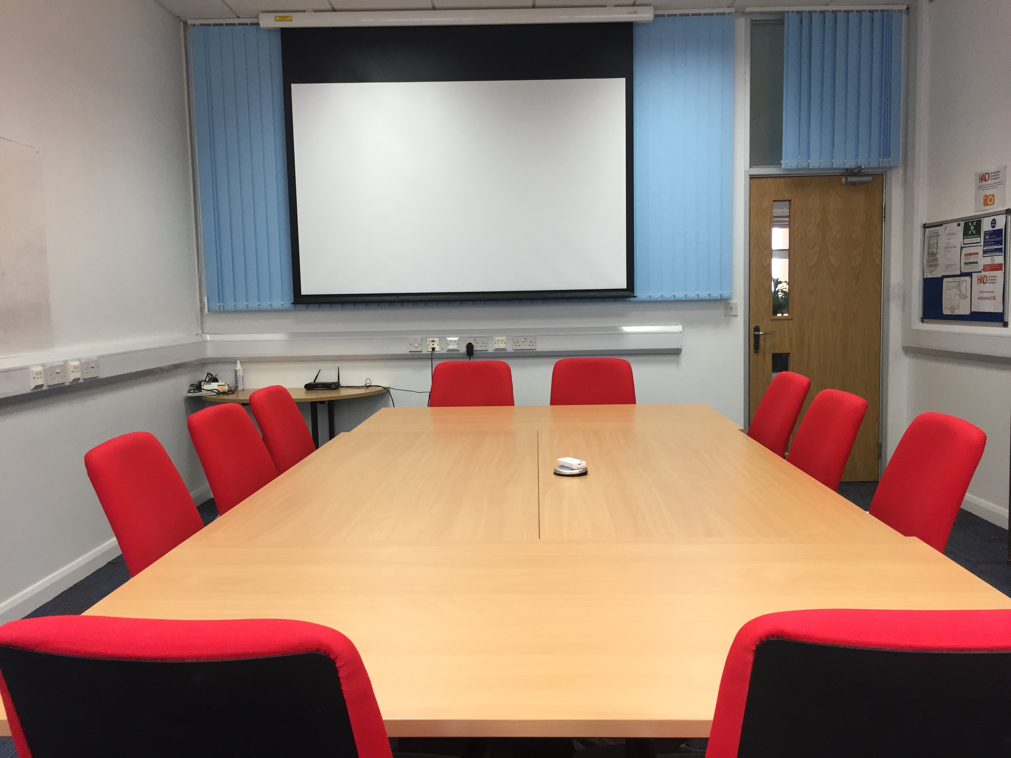 Meeting Room 5 at HAD with wooden table, red chairs for productive meetings and presentations.