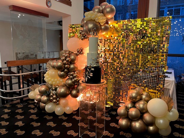 Elegant cake display with gold and white balloons at The Charter Gallery event.