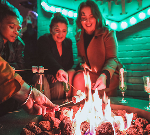 Rooftop gathering at Queen of Hoxton with fire, food, and networking vibes.