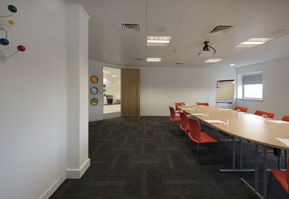 Modern meeting room at Shout in Glasgow with orange chairs, ideal for collaboration events.