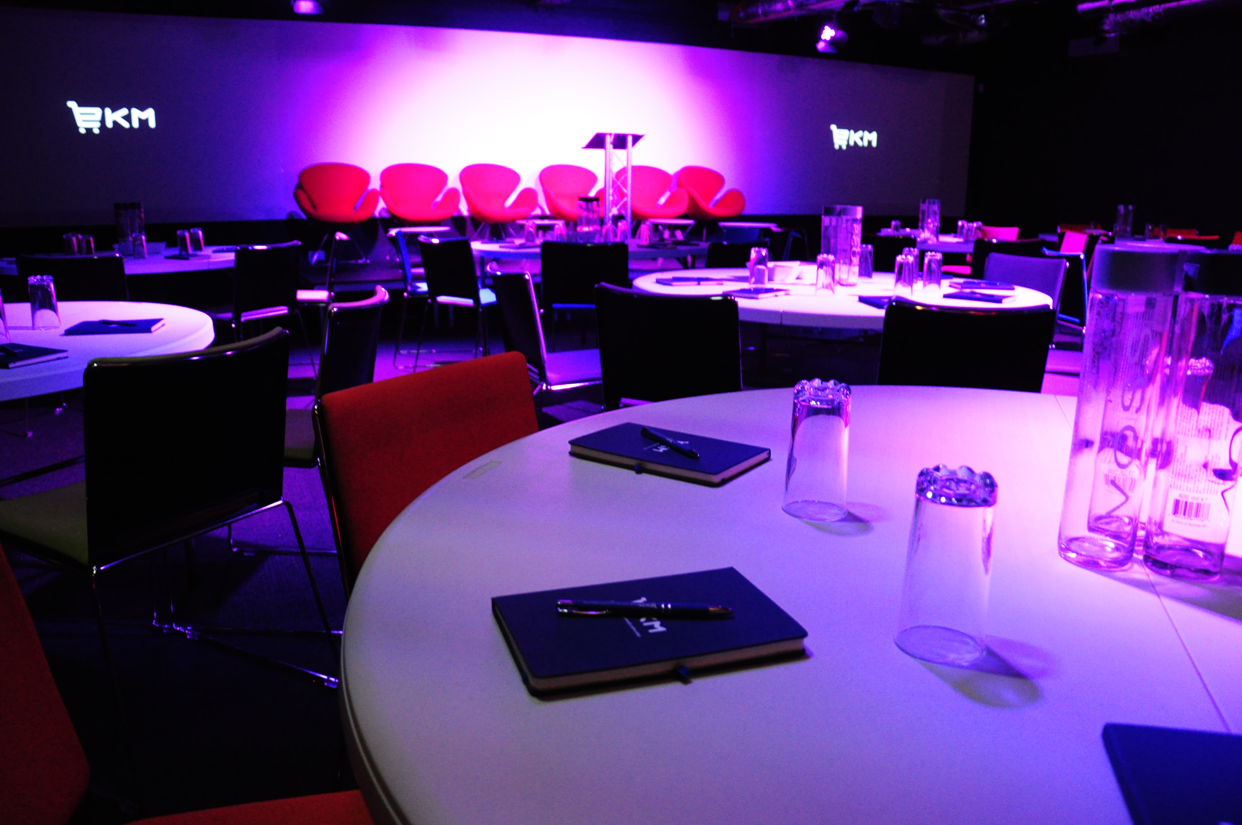 Modern auditorium with round tables set for corporate meetings and conferences.