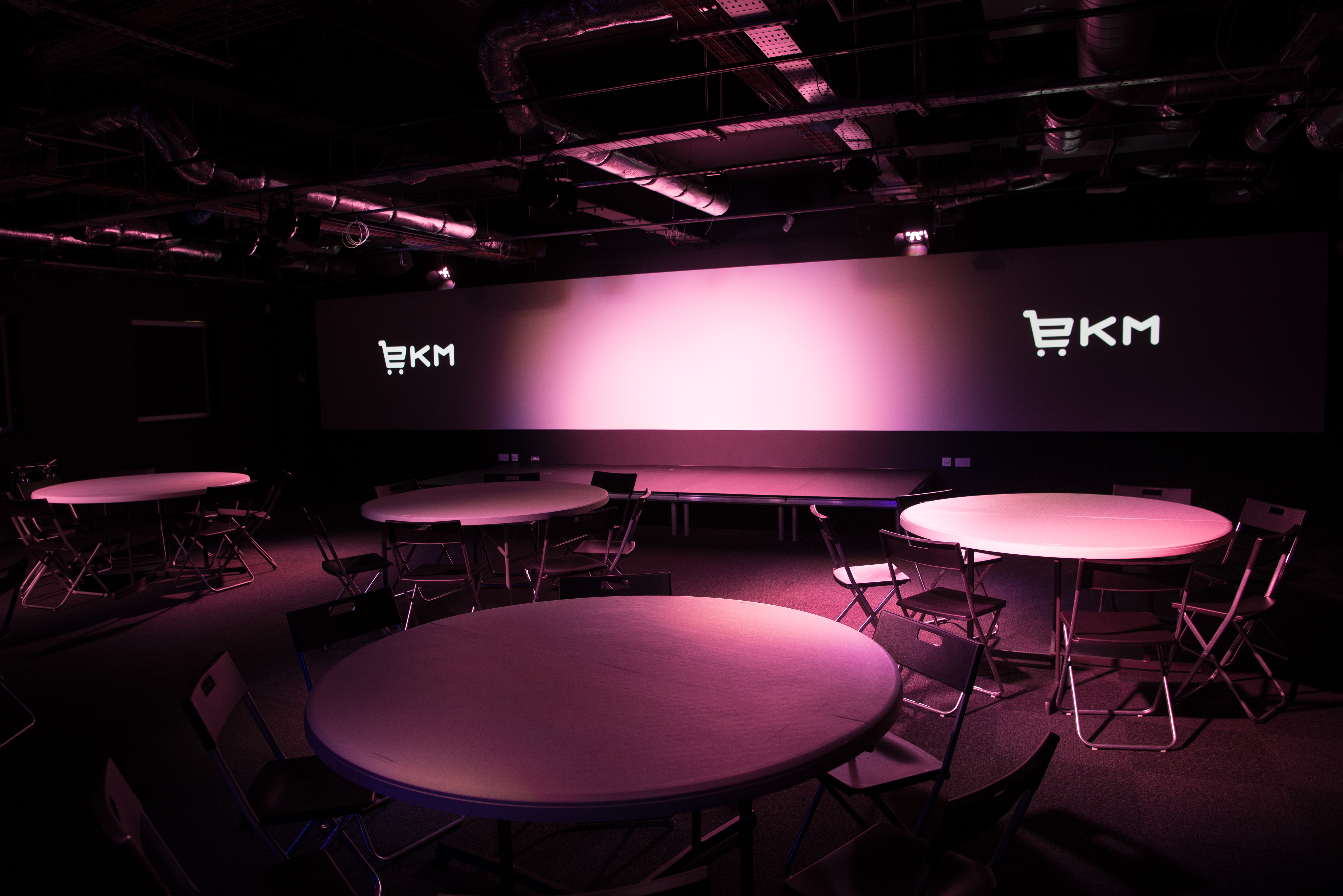 Modern auditorium with circular tables, ideal for workshops and networking events.