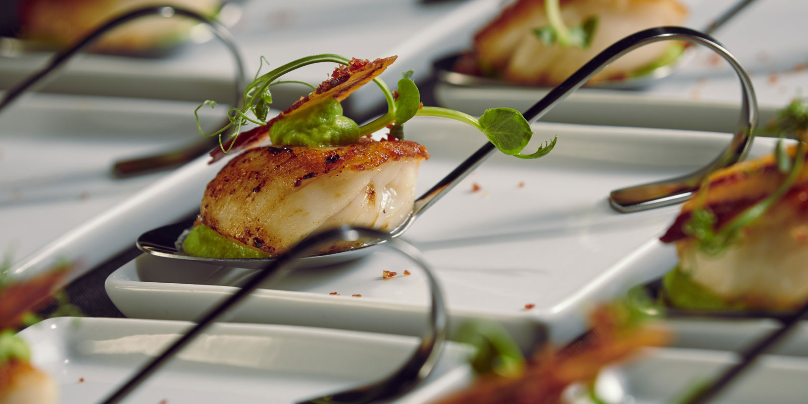 Elegant seared scallop hors d'oeuvre on spoon for upscale events and receptions.