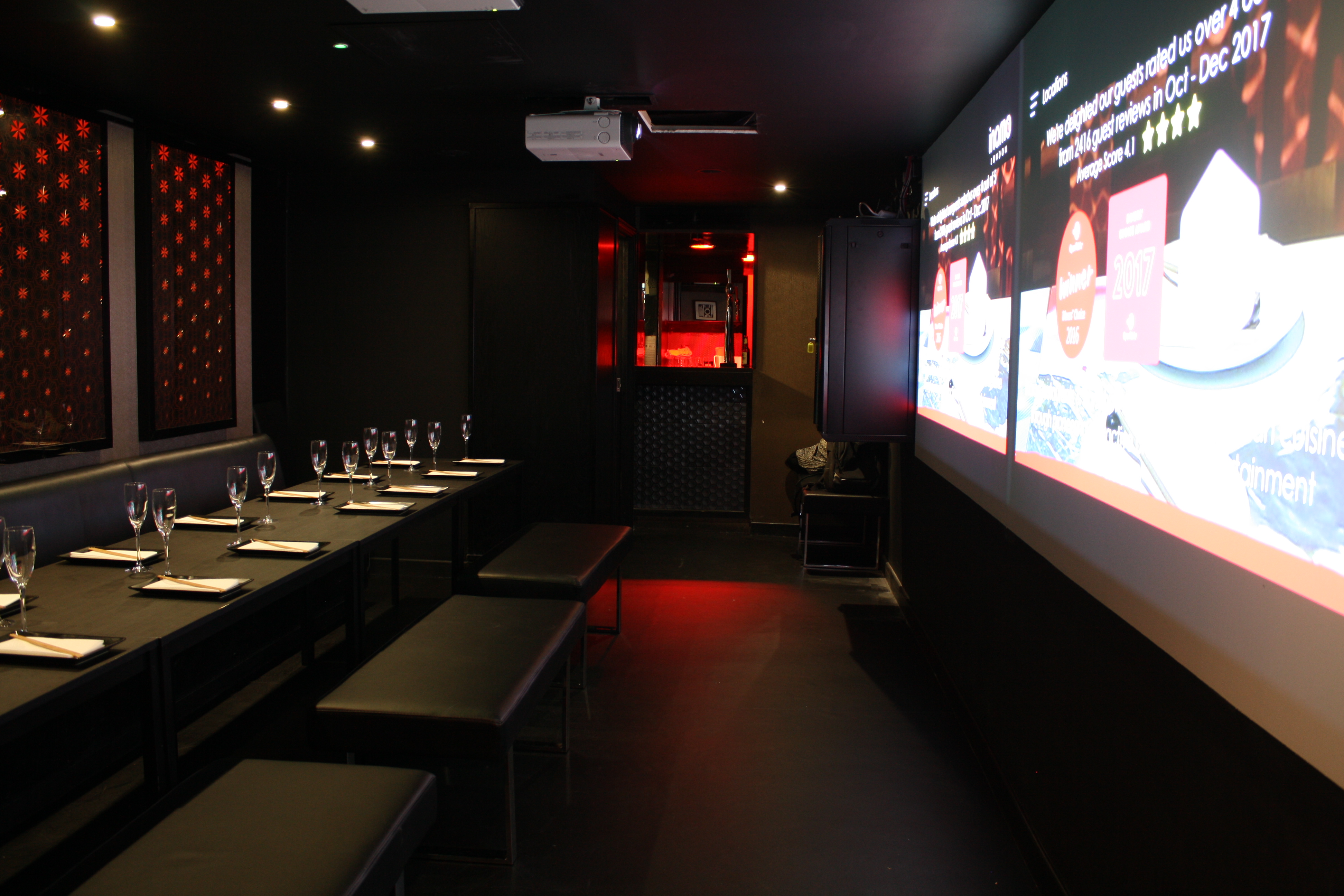 Modern event space with long table and projection screen for corporate meetings and social events.