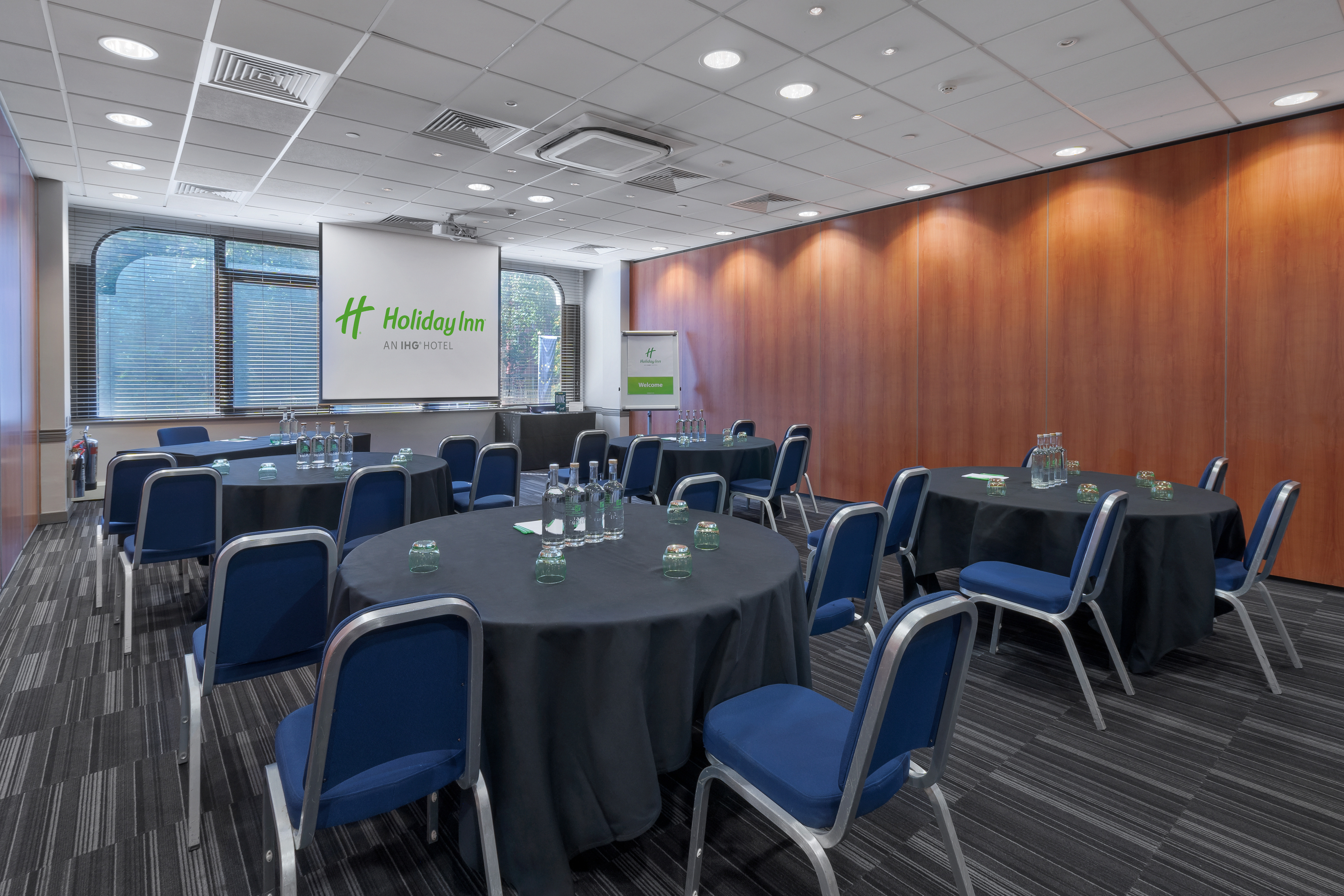 Meeting room at Holiday Inn Kensington with round tables, ideal for workshops and events.