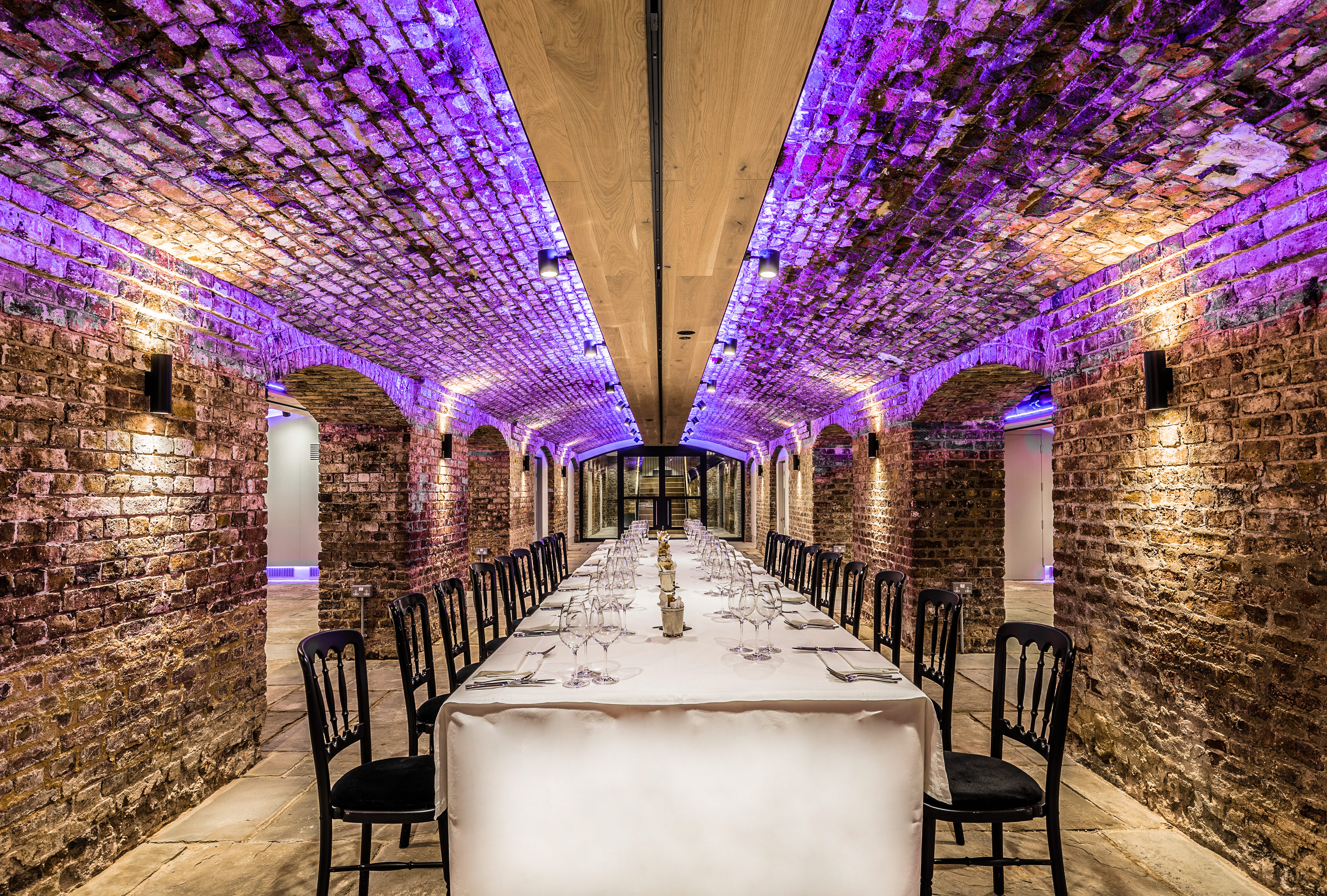 London Bridge Arches at Glaziers Hall, elegantly set table under lit brick archway for events.