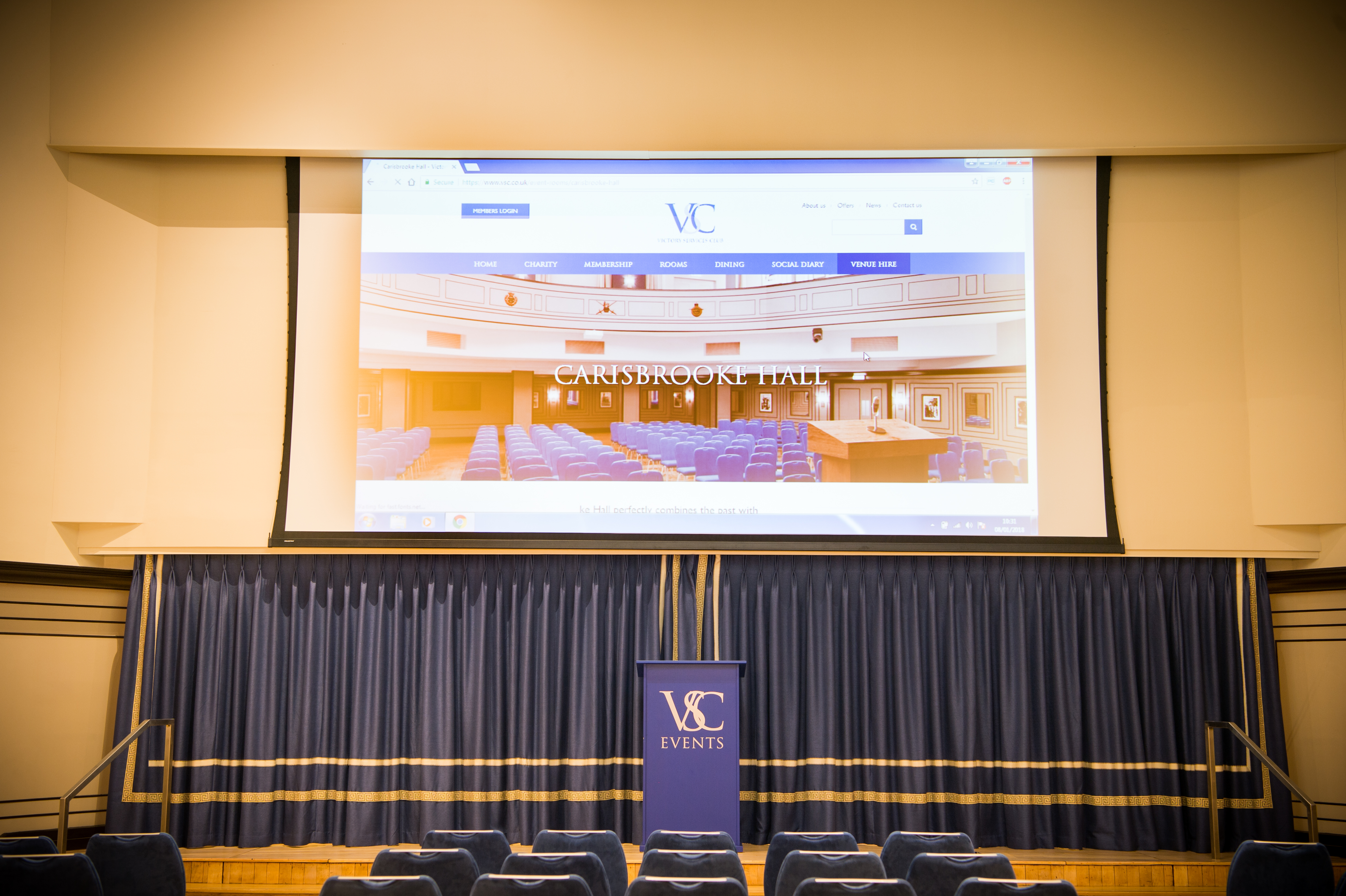 Carisbrooke Hall event space with large screen, ideal for presentations and meetings.