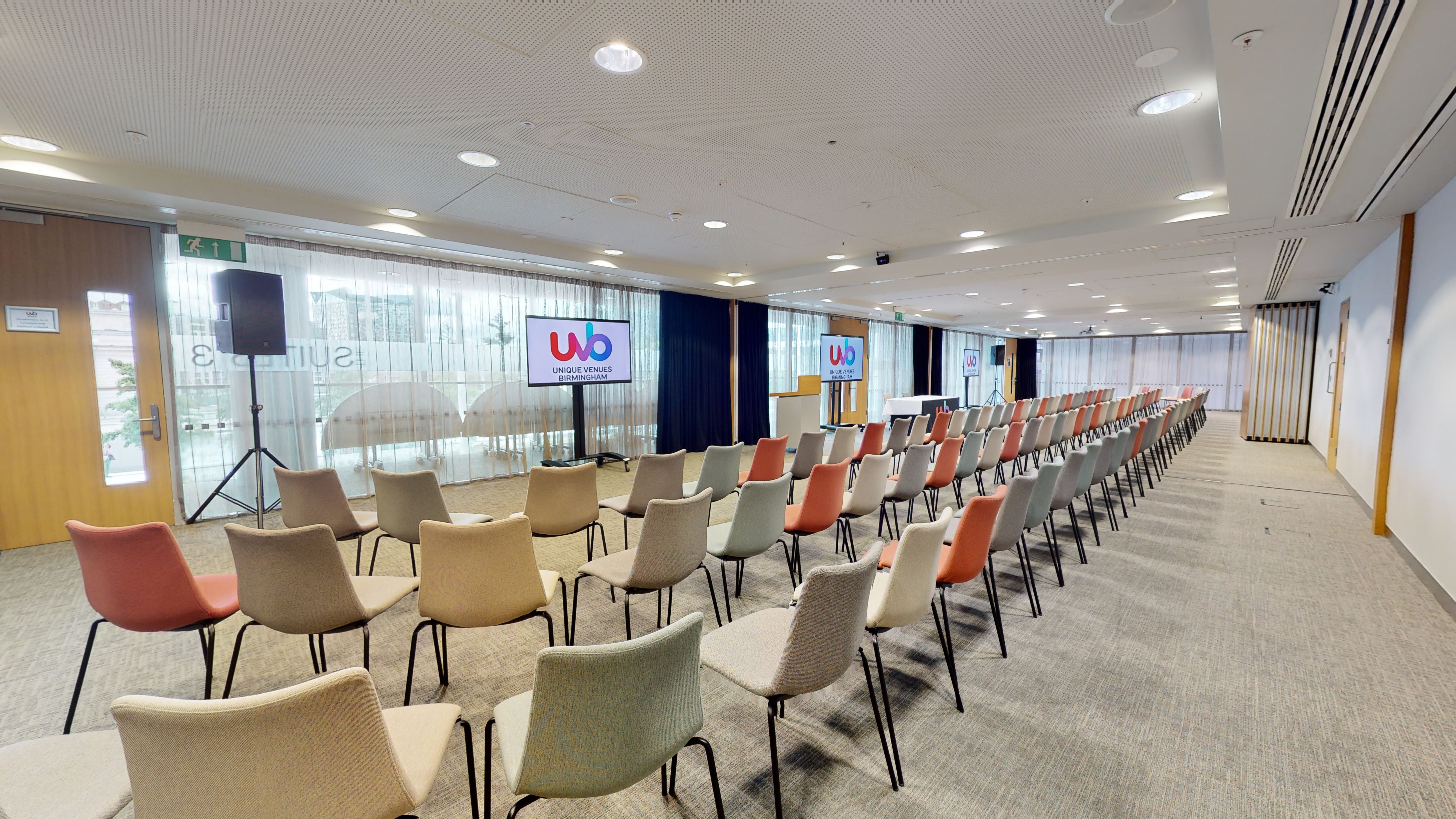 Event space with colorful chairs and dual screens for presentations in Birmingham.