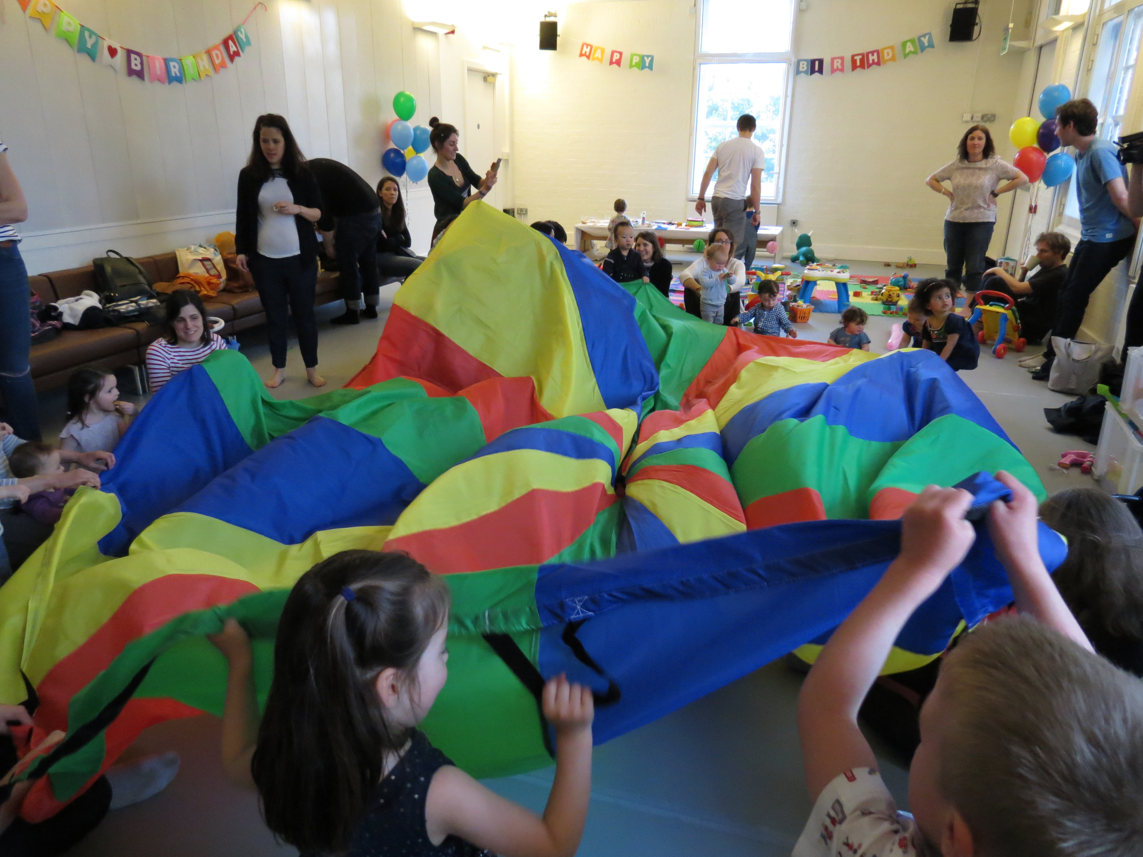 Children's party with vibrant parachute activity at Siobhan Davies Studios, engaging family fun.