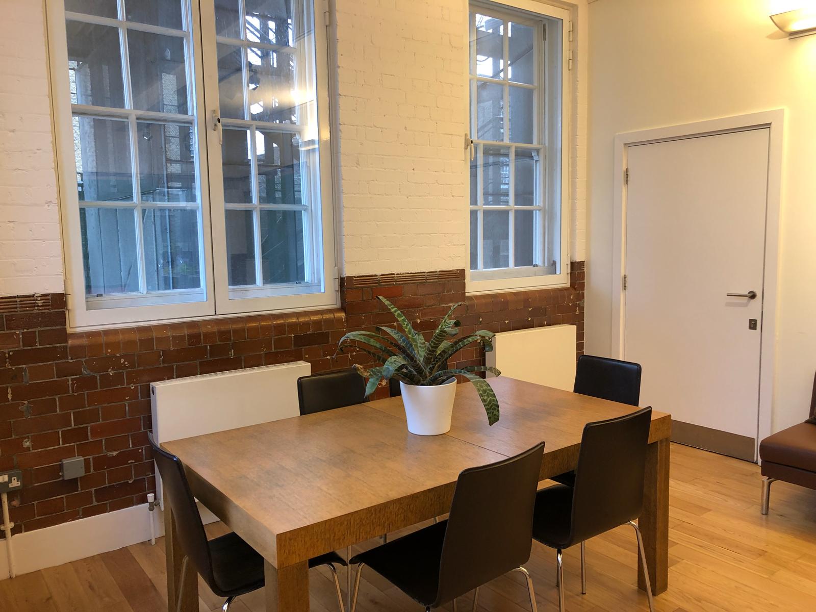 Well-lit meeting room with wooden table and black chairs at Siobhan Davies Studios.