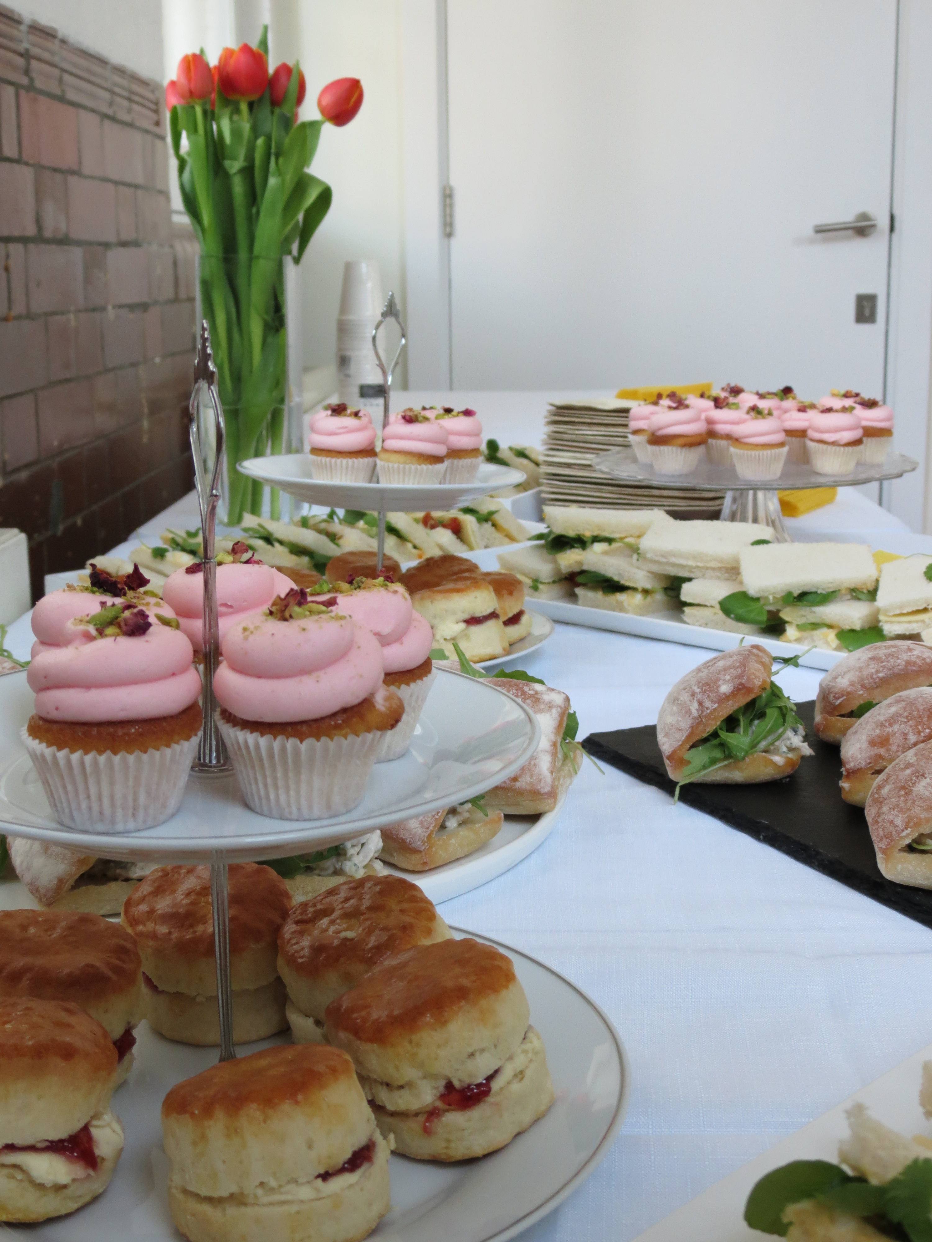 Elegant refreshments with pink cupcakes and savory sandwiches for event gatherings.