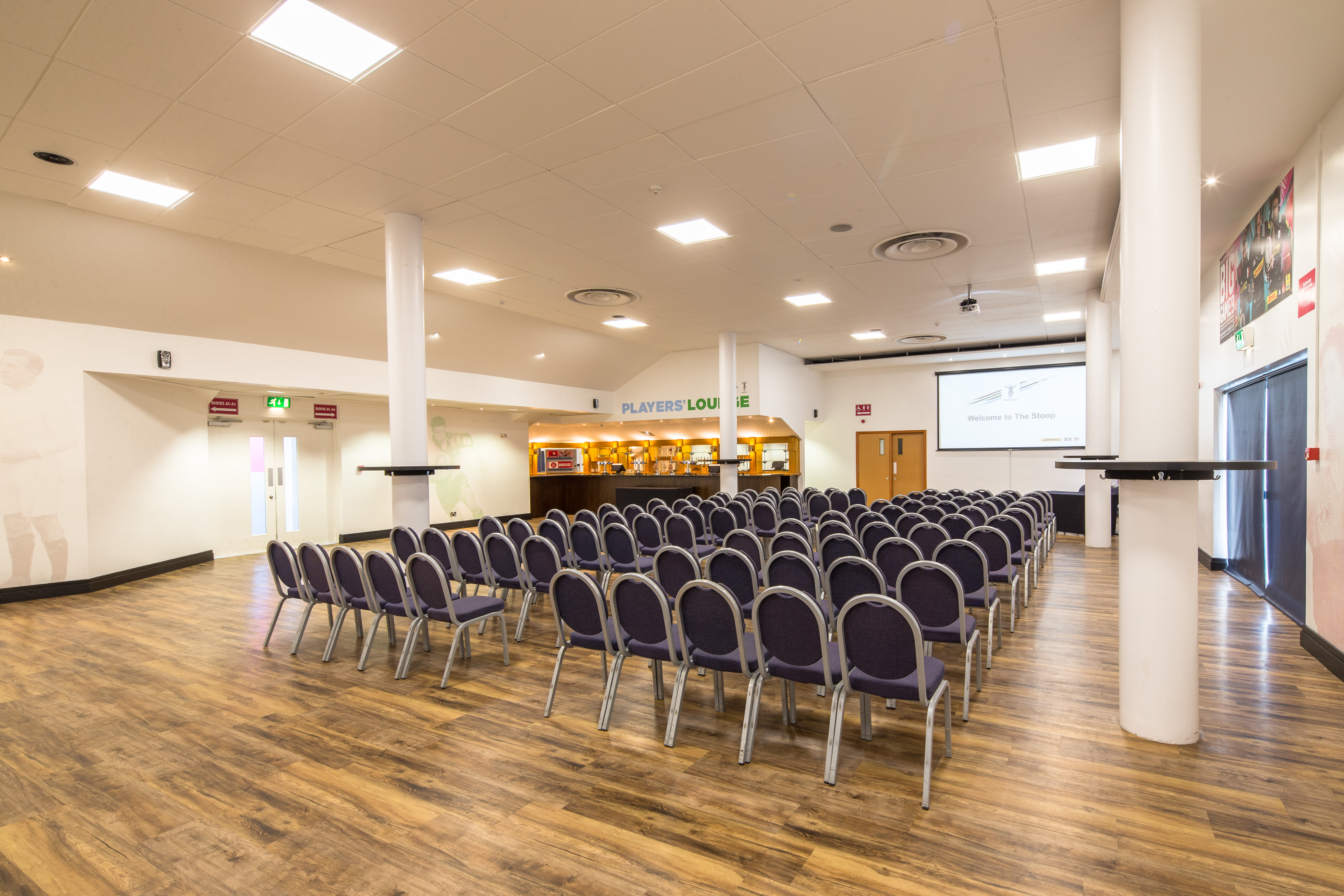 Players in Twickenham Stoop Stadium set for a conference presentation with chairs arranged.