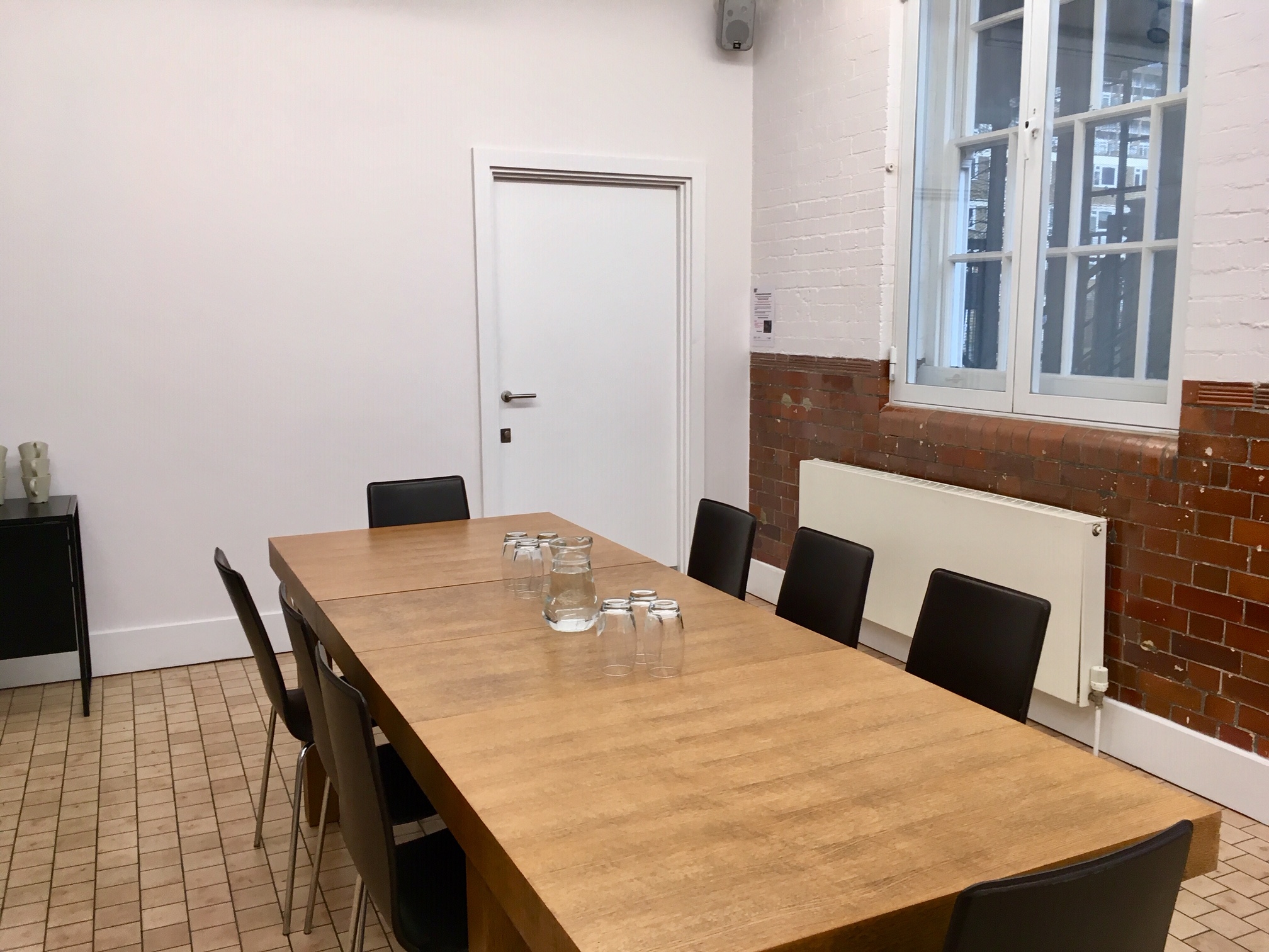 Minimalist meeting room with wooden table, ideal for workshops and planning.