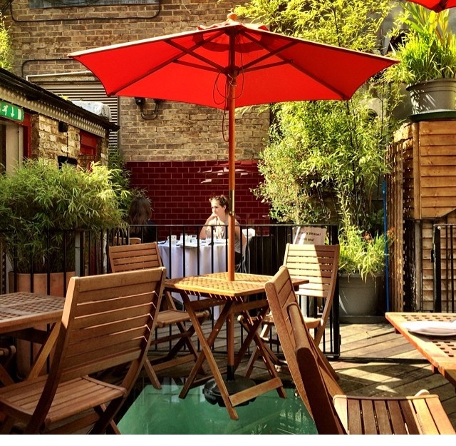 Outdoor dining area at The Union Club with red umbrella, perfect for networking events.