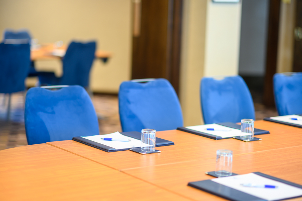 "Allenby Room meeting setup with polished table, notepads, and blue chairs at Victory Services Club"