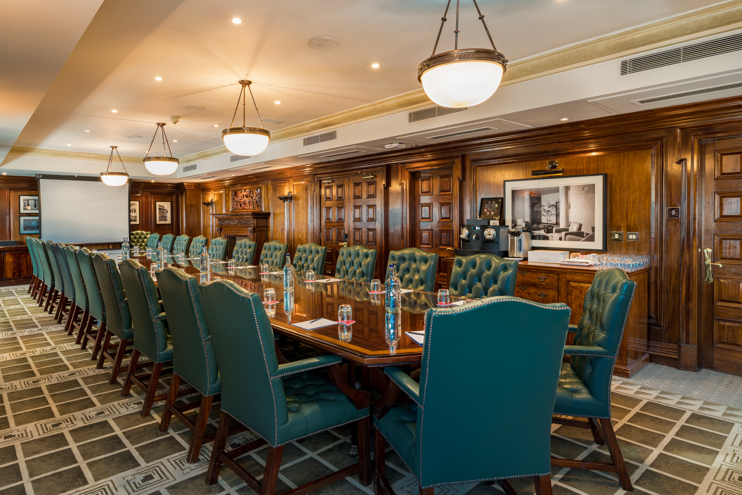 Sophisticated boardroom with wooden table and green leather chairs for corporate events.