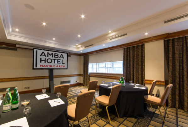 Meeting room at Amba Hotel Marble Arch, round tables set for corporate events.