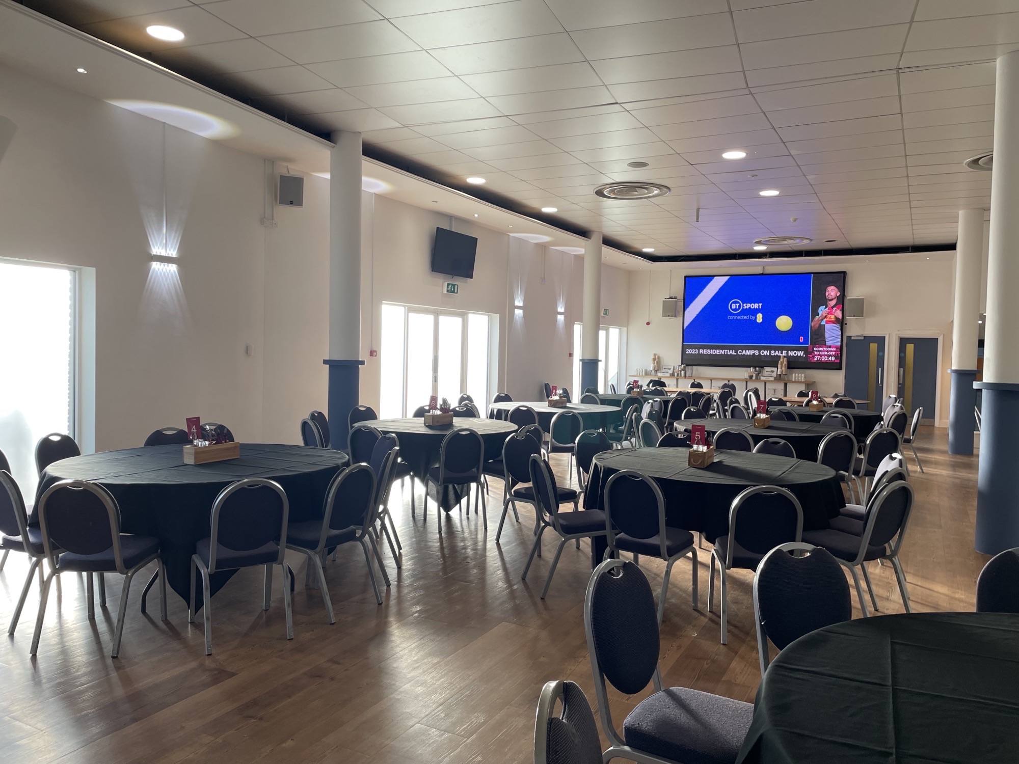 Debentures meeting setup at Twickenham Stoop Stadium with round tables and natural light.