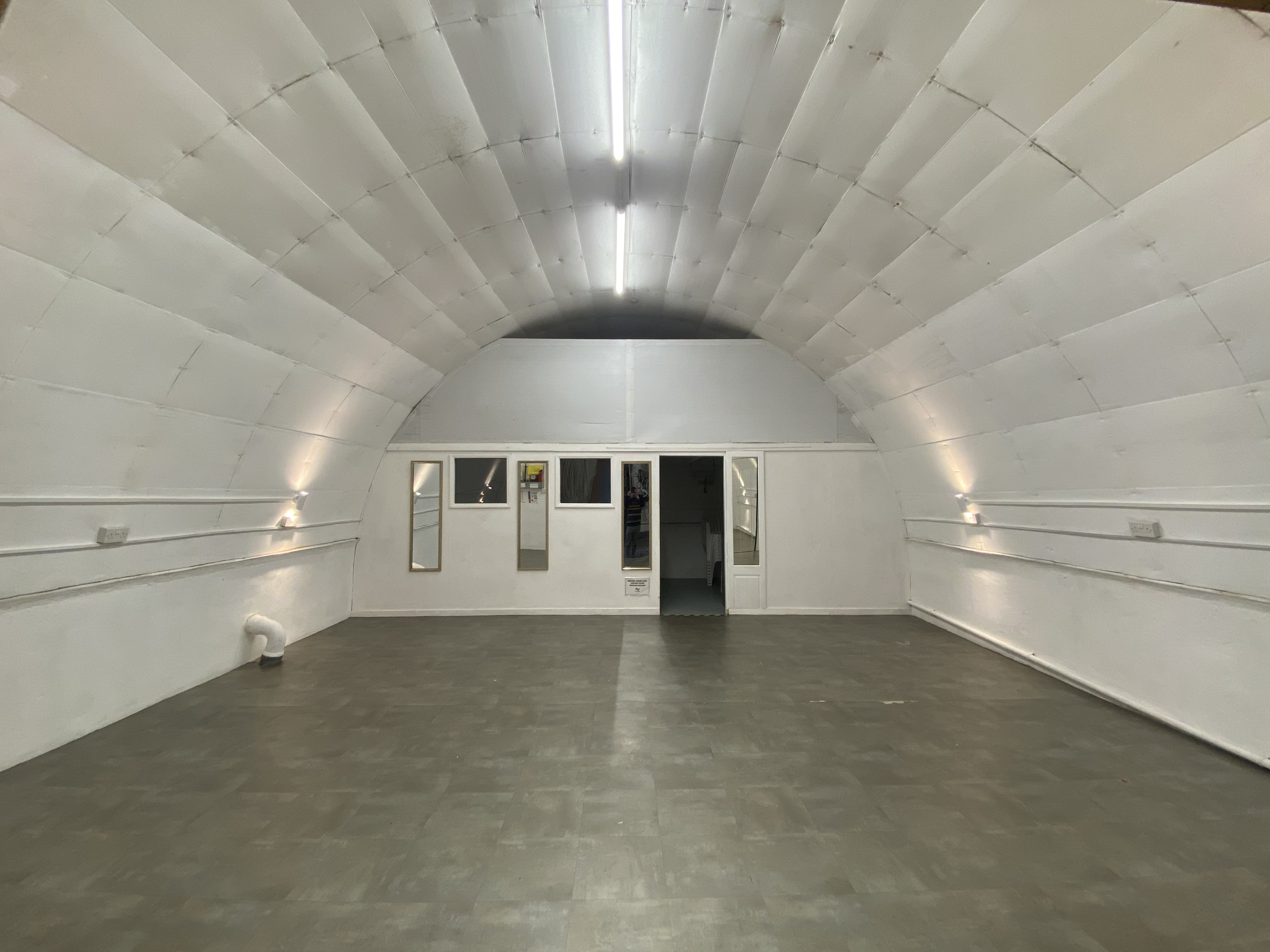 Versatile minimalist event space with arched ceiling for workshops and exhibitions.