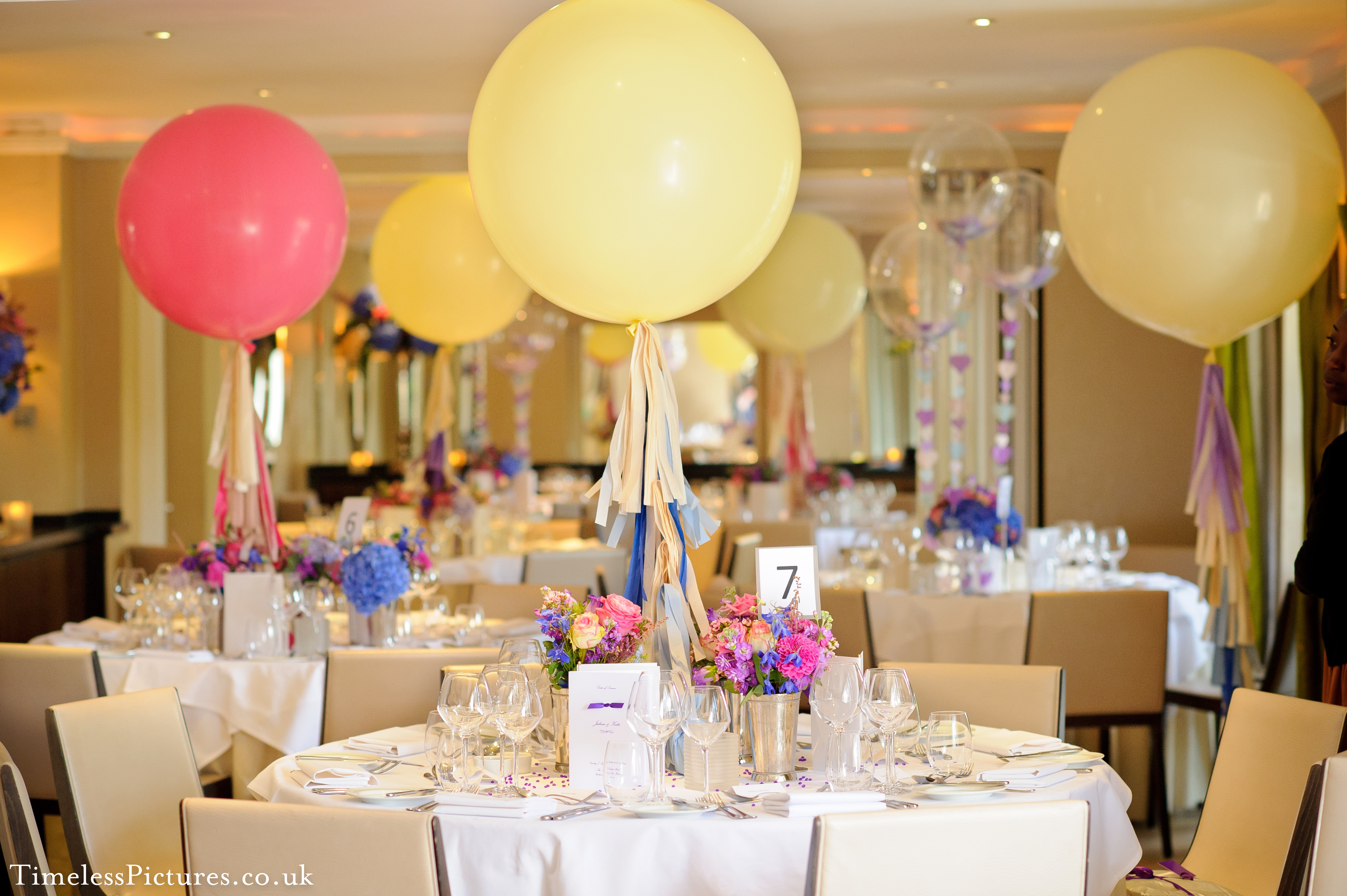 Elegant event space with floral centerpieces and pastel balloons, perfect for weddings or parties.
