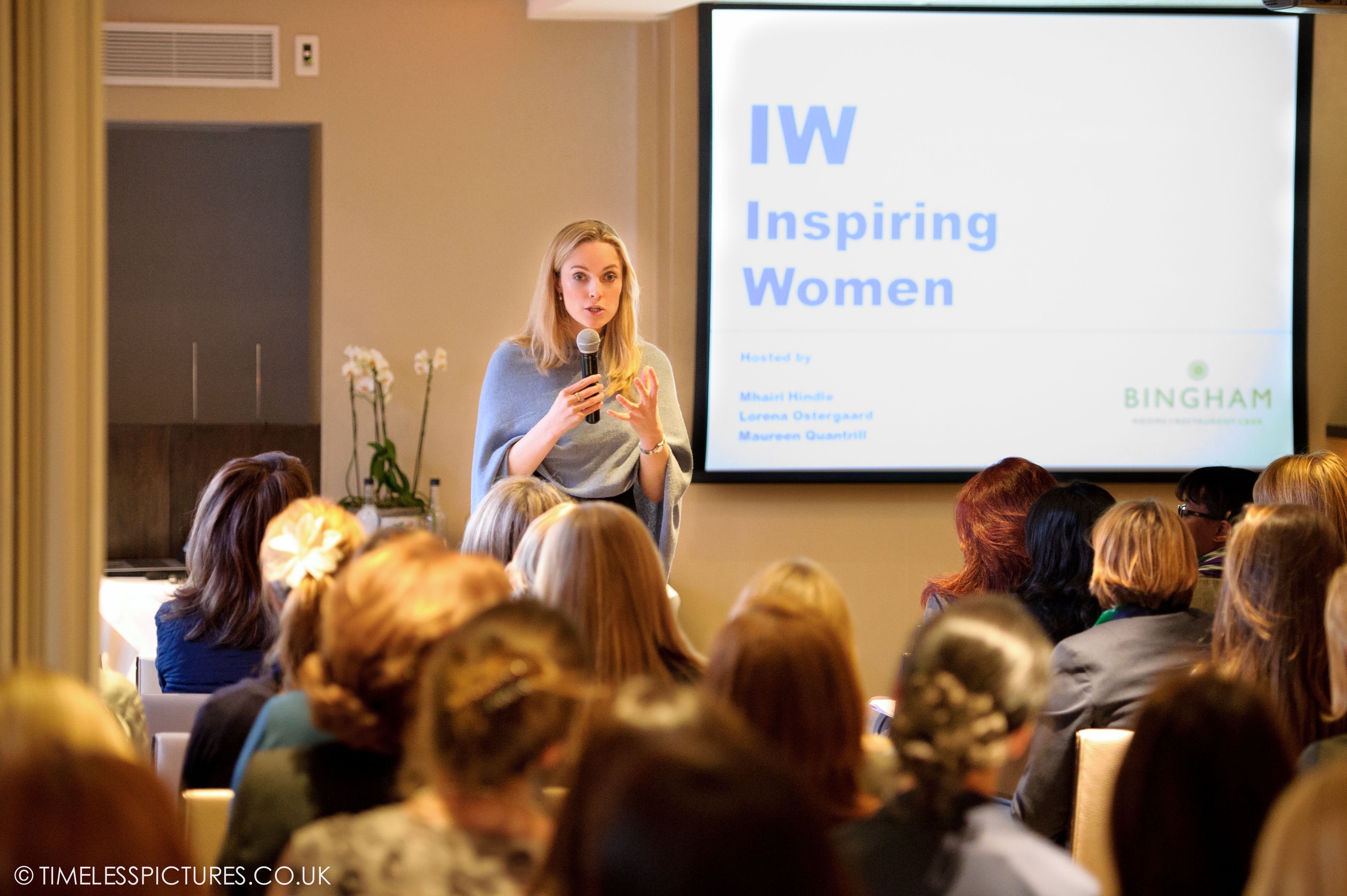 Professional speaker engaging audience in intimate Garden Room 3 at "Inspiring Women" event.