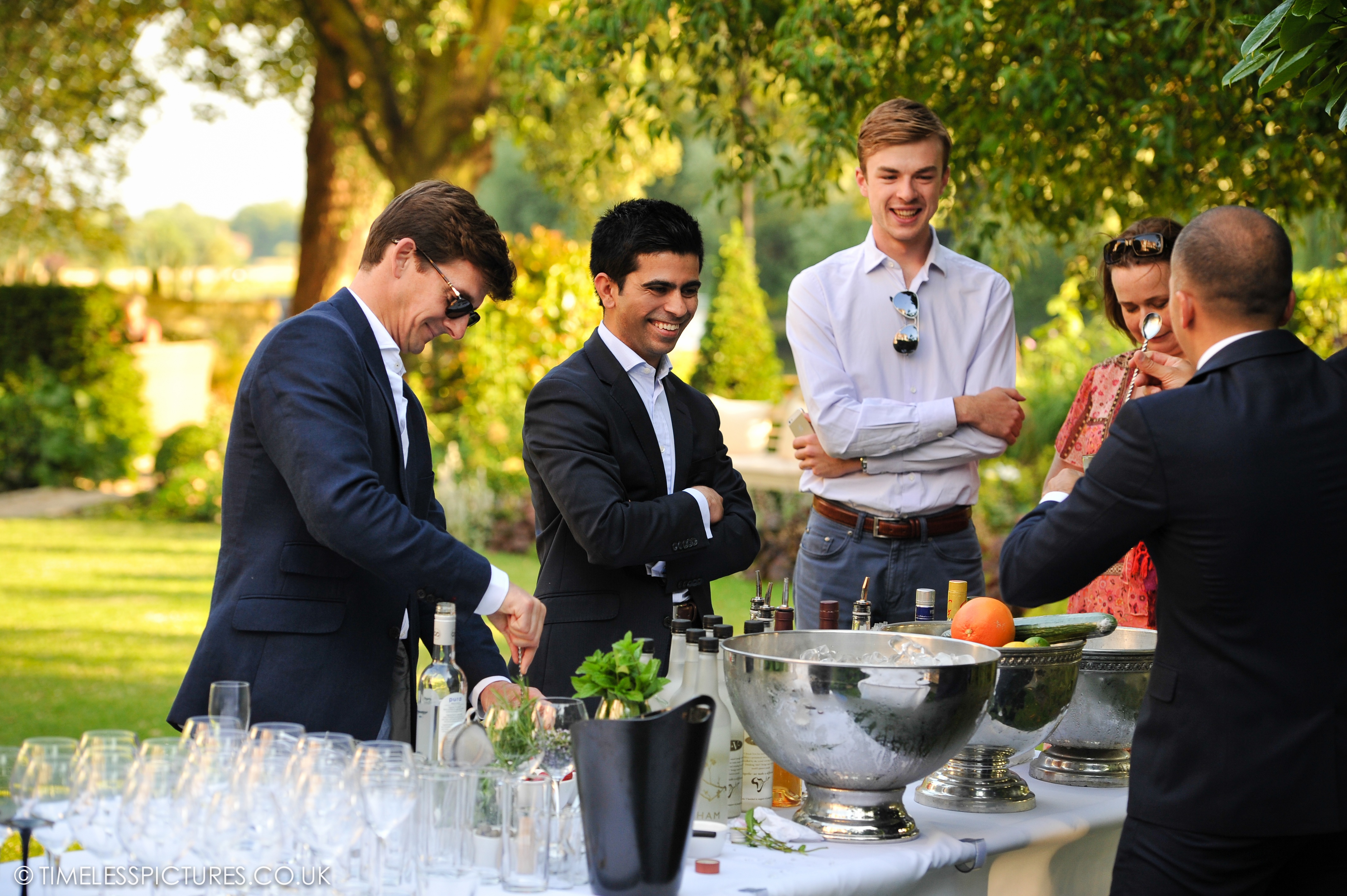 Sophisticated outdoor networking event in lush garden rooms with refreshments.