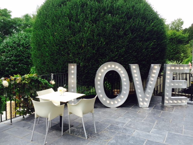 Outdoor wedding venue with illuminated "LOVE" letters and elegant table arrangements.