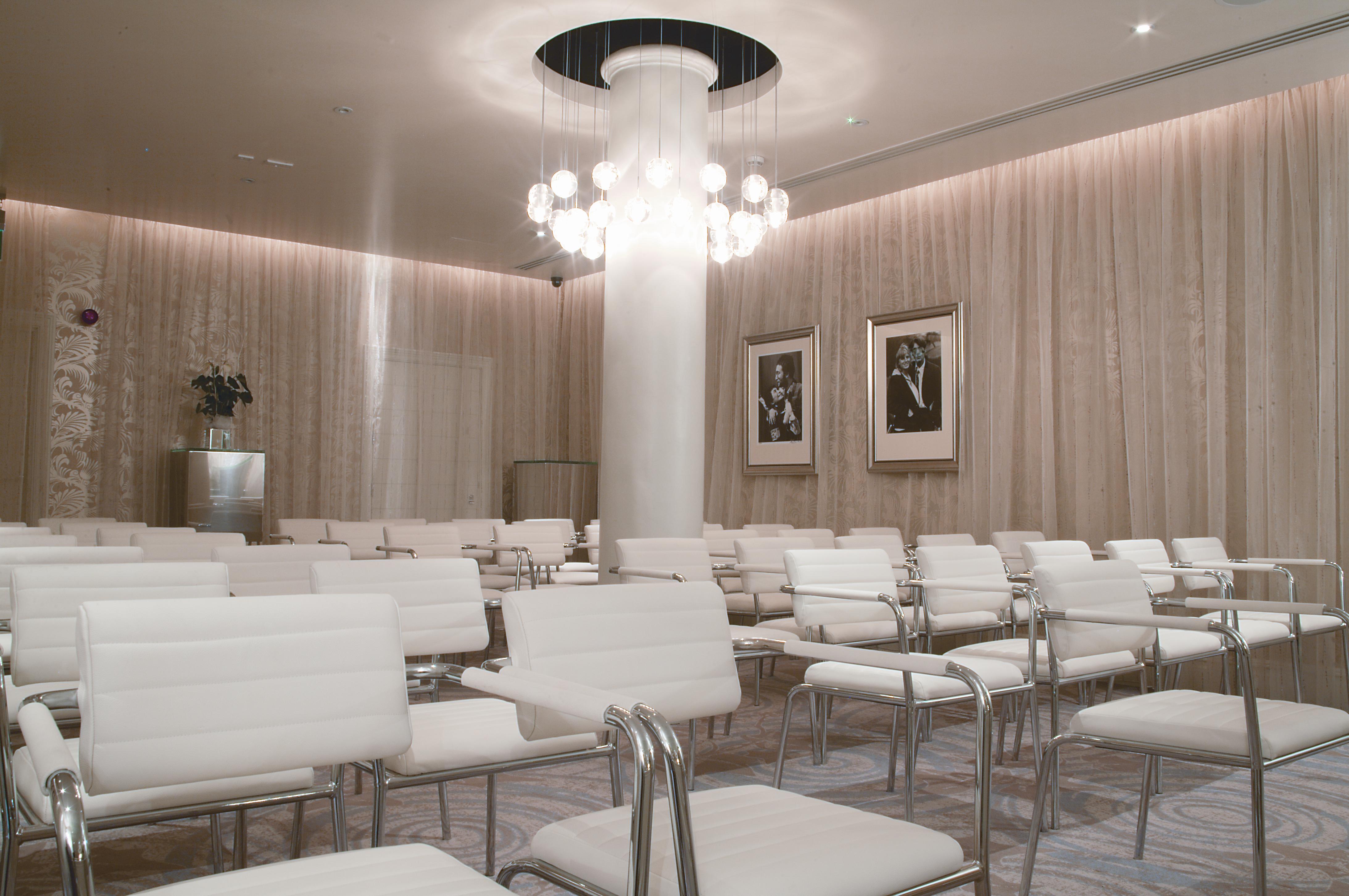 Modern event space with white chairs and chandelier at Hard Days Night Hotel.