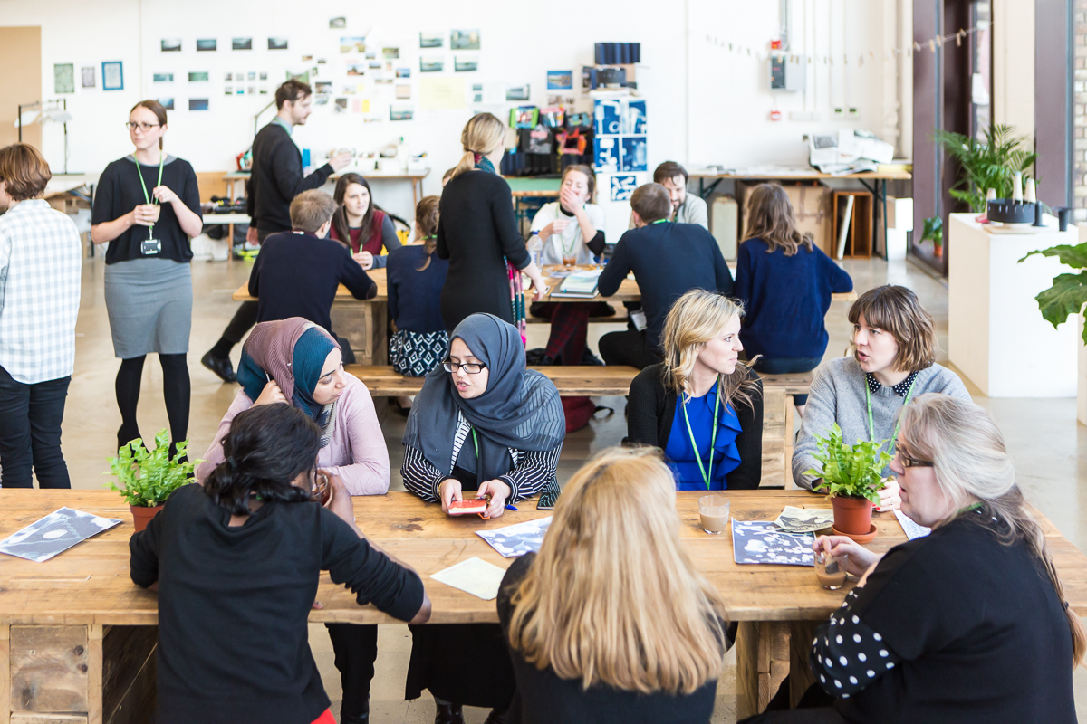 Vibrant networking event on Mezanine Floor at R.A.W Labs with communal tables and greenery.