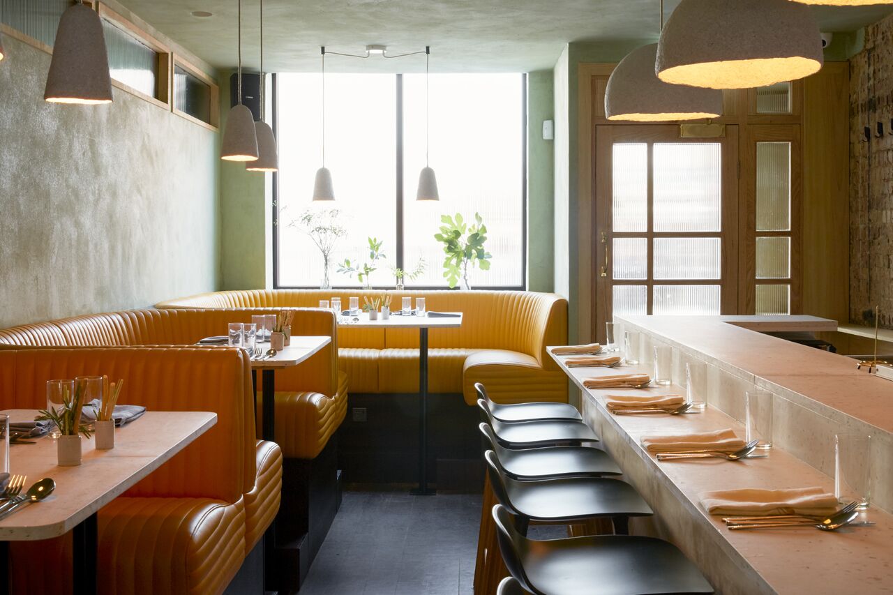 Stylish restaurant interior with cozy yellow banquettes, ideal for networking lunches.