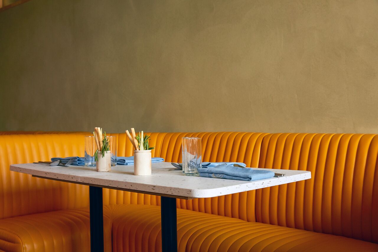 Stylish restaurant dining setup with vibrant orange seating for intimate events.