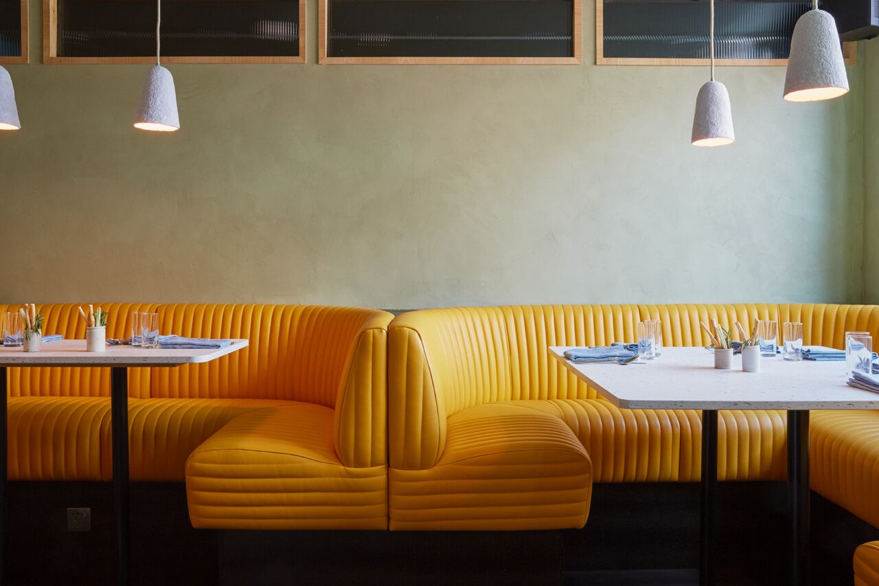 Modern restaurant with vibrant yellow seating, ideal for casual meetings and events.