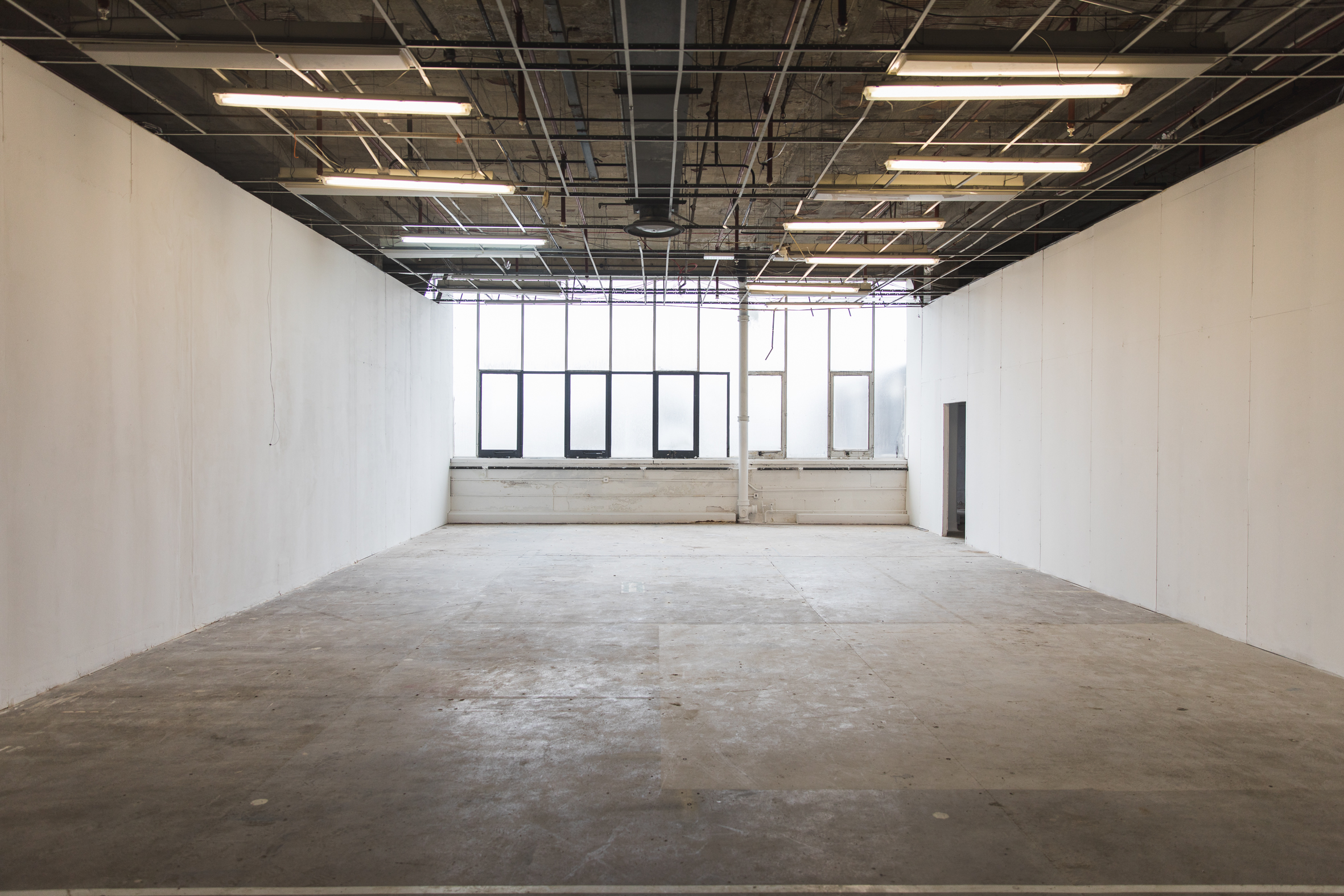 Spacious minimalist gallery with large windows, ideal for conferences and workshops.