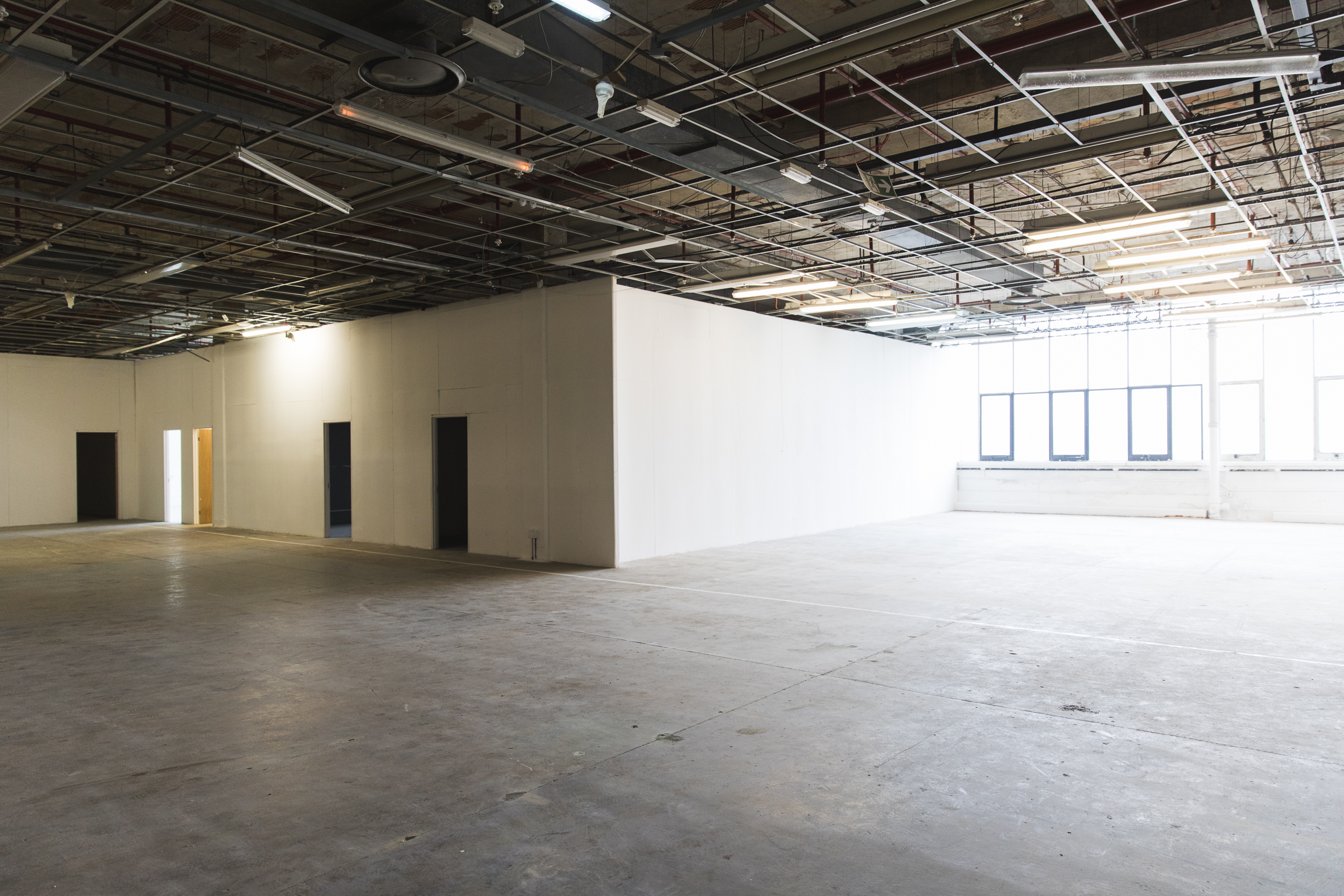 Spacious unfinished event venue with high ceilings, ideal for corporate gatherings and workshops.