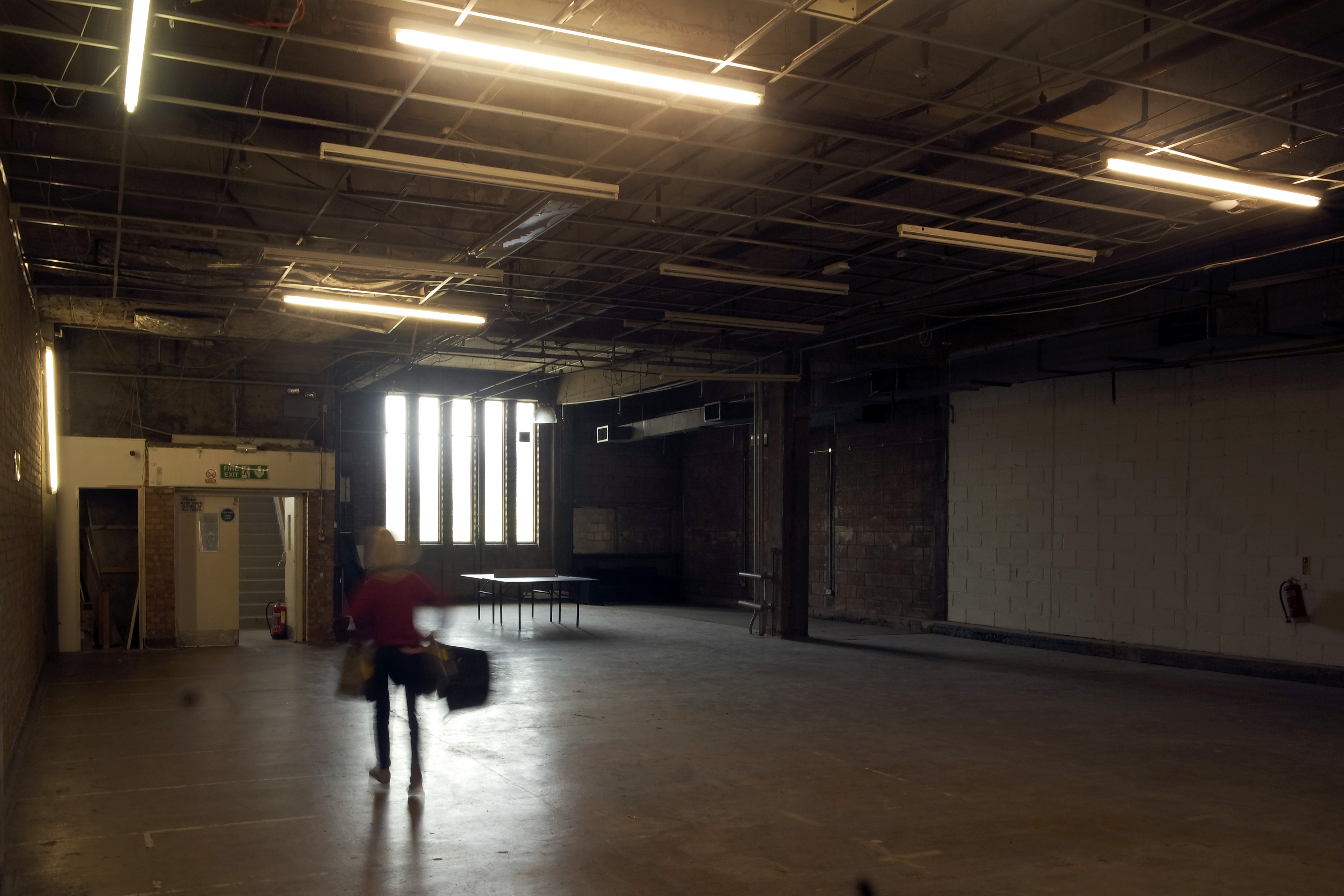 Spacious industrial event space with high ceilings and exposed lighting, perfect for creative gatherings.