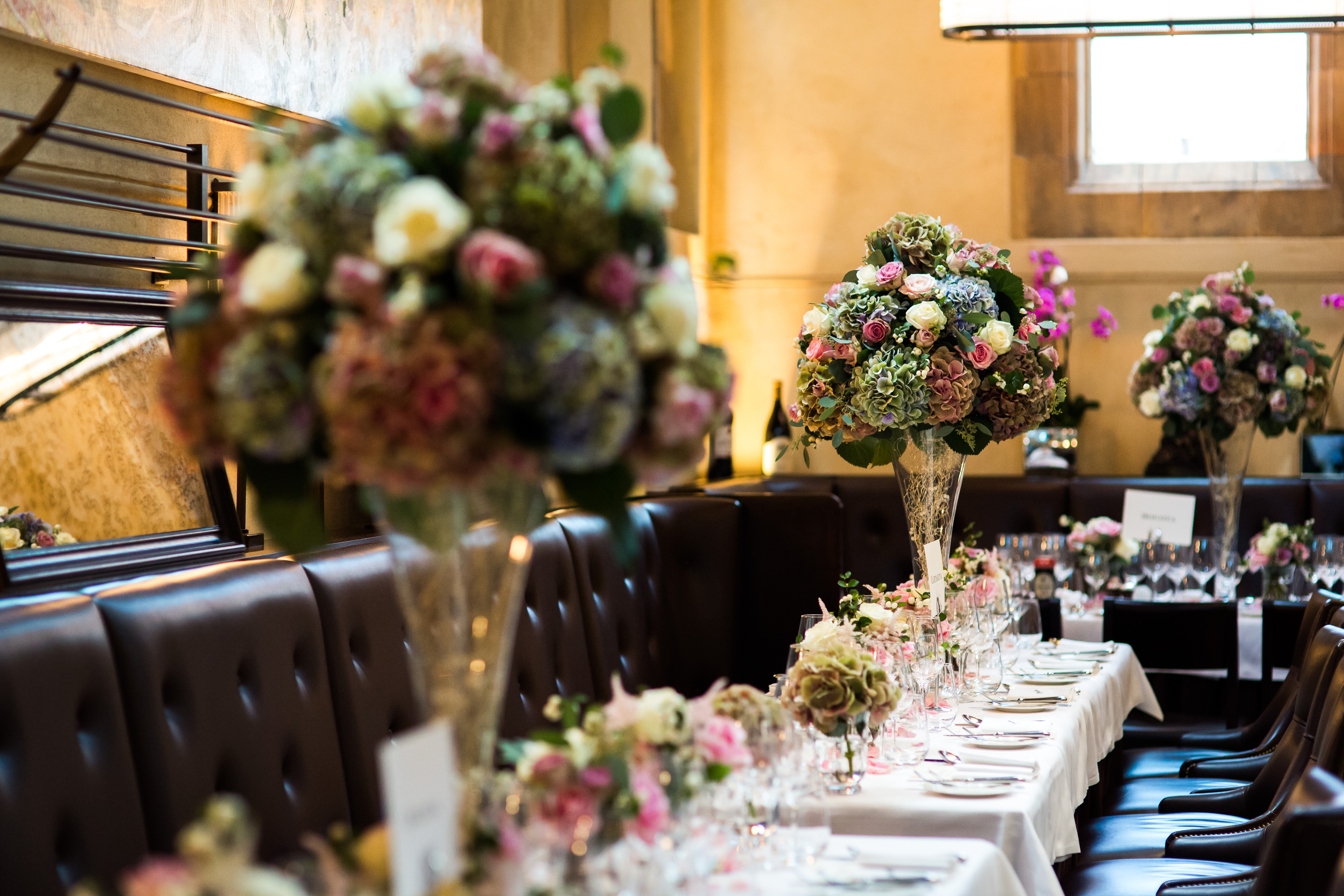 Elegant dining setup with tall floral centerpieces for weddings and corporate events.