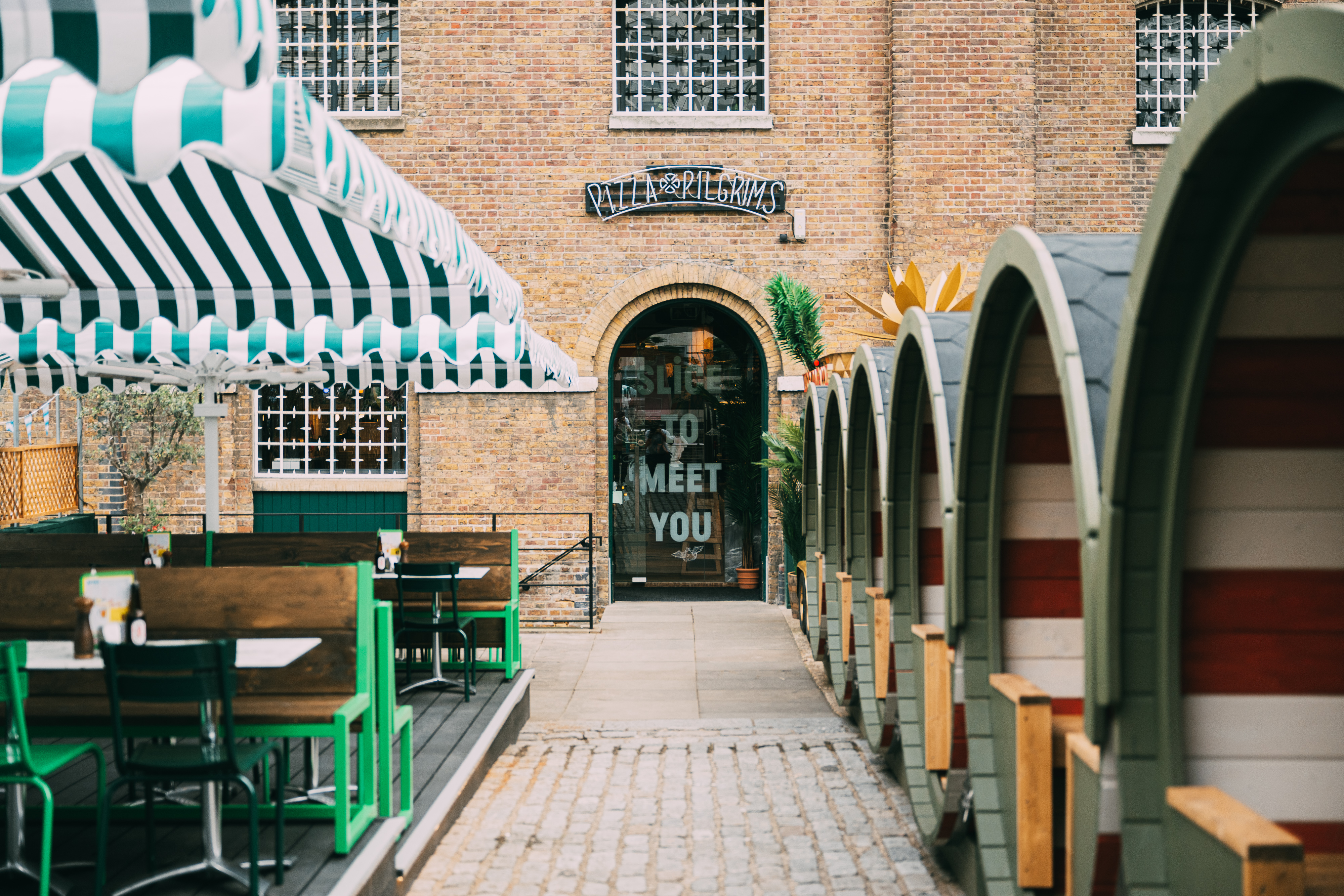 Outdoor terrace at Pizza Pilgrims with striped canopies for casual gatherings and networking.
