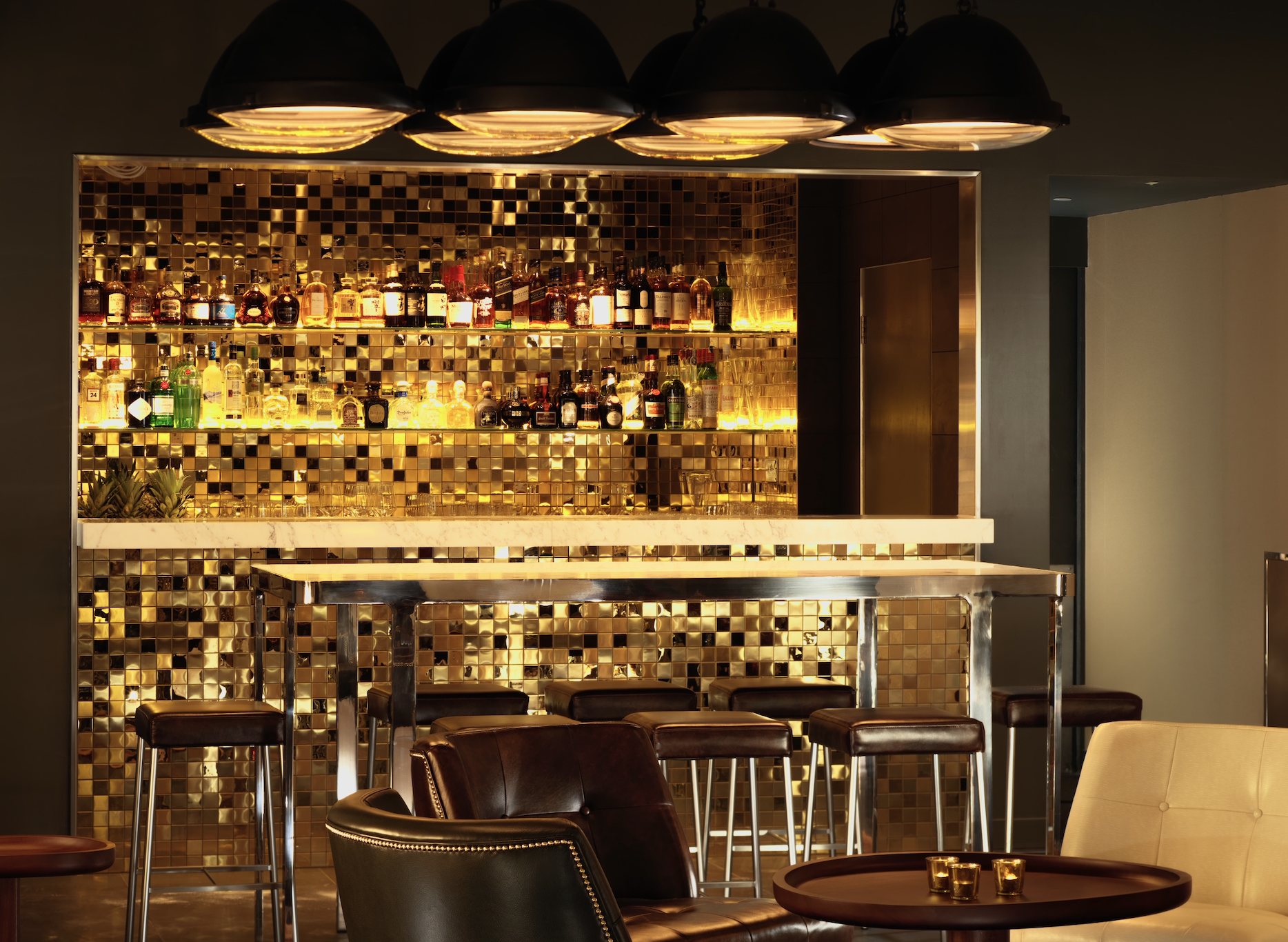 Sleek bar with gold mosaic backdrop, perfect for upscale cocktail receptions and events.