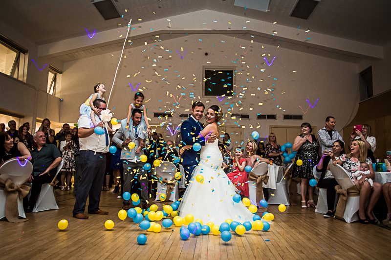 Vibrant wedding celebration at Gamlingay Eco Hub with confetti and balloons.